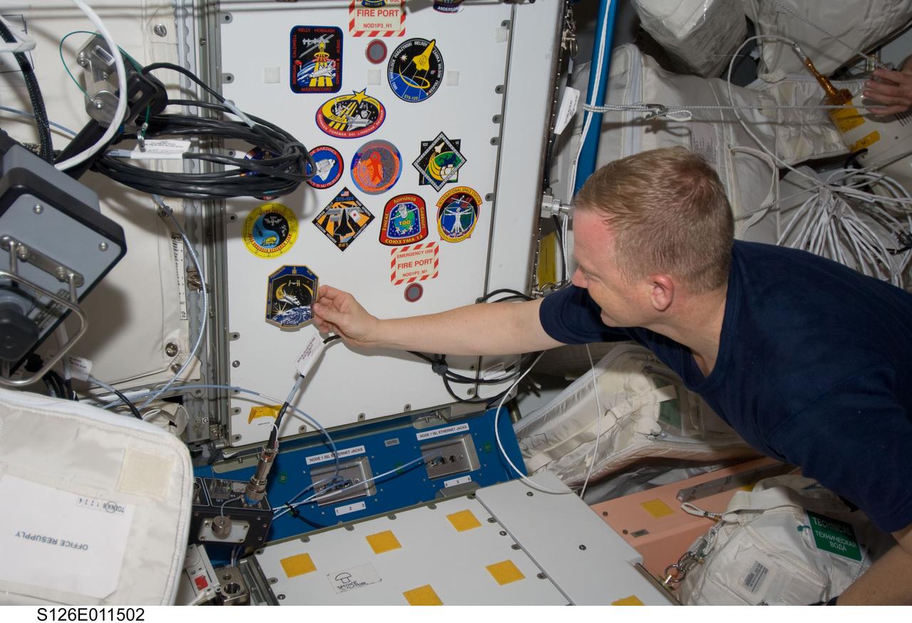 S126-E-011502 (26 Nov. 2008) --- Continuing a longstanding tradition, astronaut Eric Boe, STS-126 pilot, adds his crew patch in the Unity node to the growing collection of those representing shuttle crews who have worked on the International Space Station.