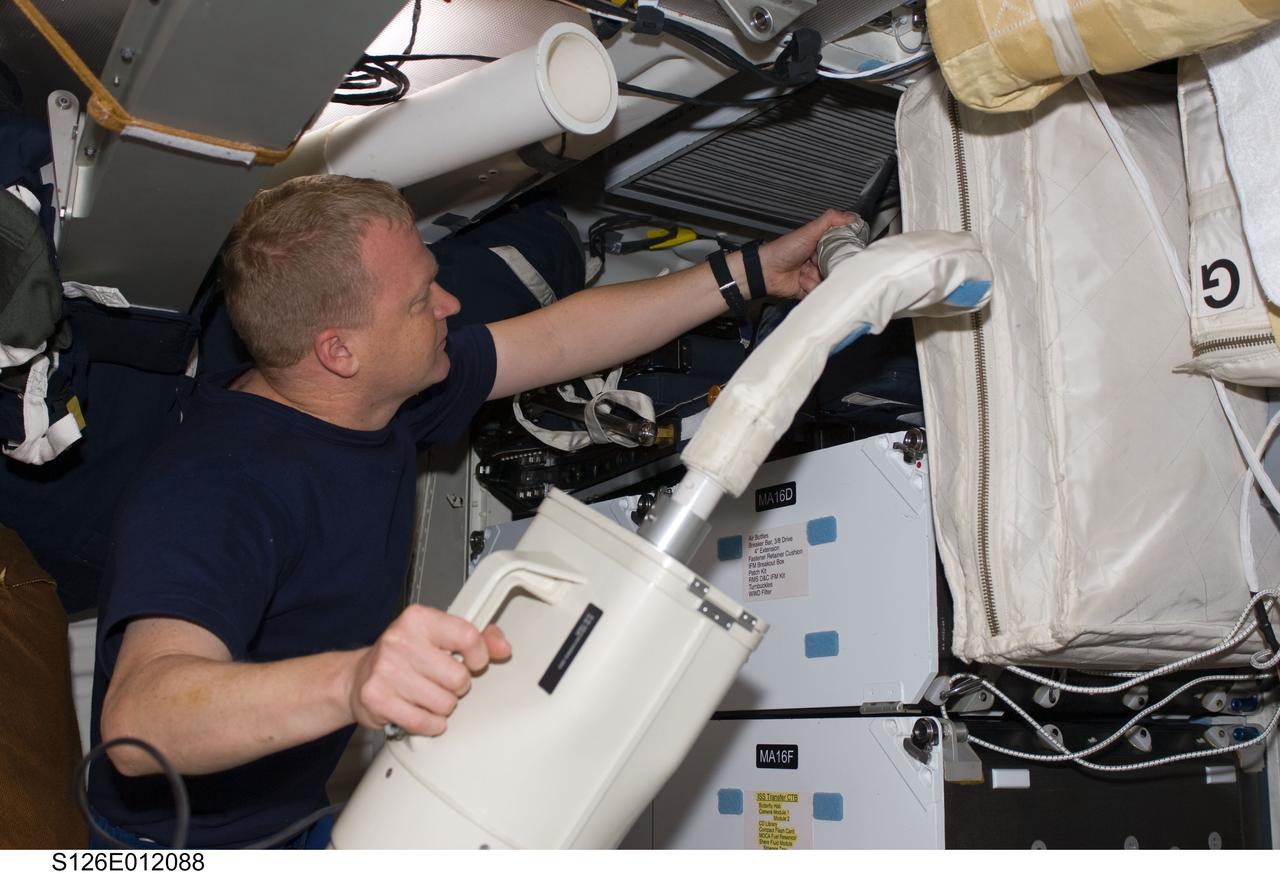 S126-E-012088 (27 Nov. 2008) --- Having completed the current home improvement project with other members of the joint space shuttle-International Space Station aggregation aboard the orbital outpost, astronaut Eric Boe turns to housekeeping chores aboard Endeavour. The pilot uses a vacuum cleaner to remove dust particles from the air filter system on the shuttle's middeck.