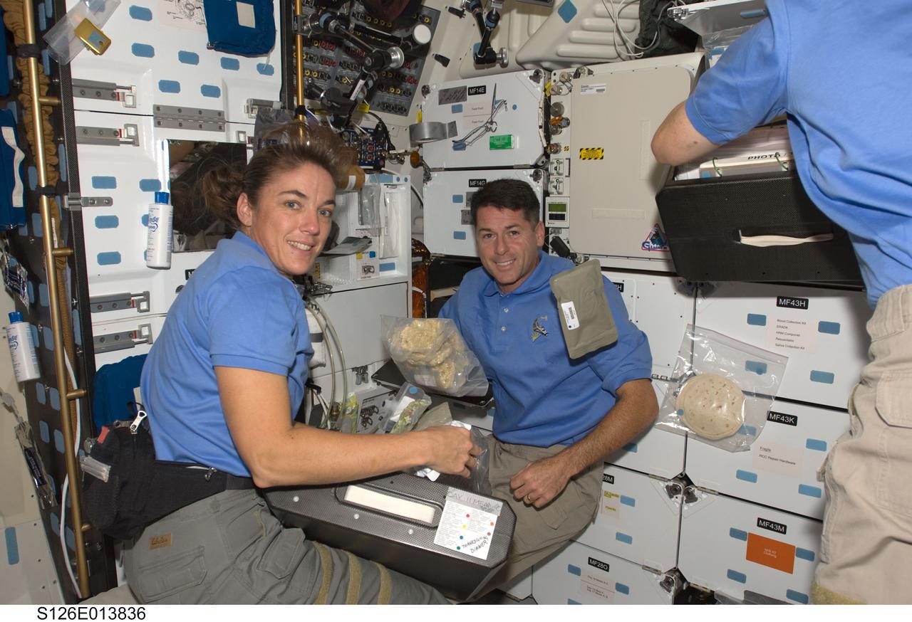 S126-E-013836 (27 Nov. 2008) --- Stationed near the shuttle's galley and stowage lockers, astronauts Heidemarie Stefanyshyn-Piper and Shane Kimbrough, STS-126 mission specialists, assemble the elements of Thanksgiving dinner on the middeck of the Space Shuttle Endeavour, while the orbiter is docked with the International Space Station. A Russian cosmonaut and seven other astronauts are not far away from the scene and all ten shared the meal and observance at a common place and time, on the eve of the scheduled Nov. 28 undocking of the shuttle and station.