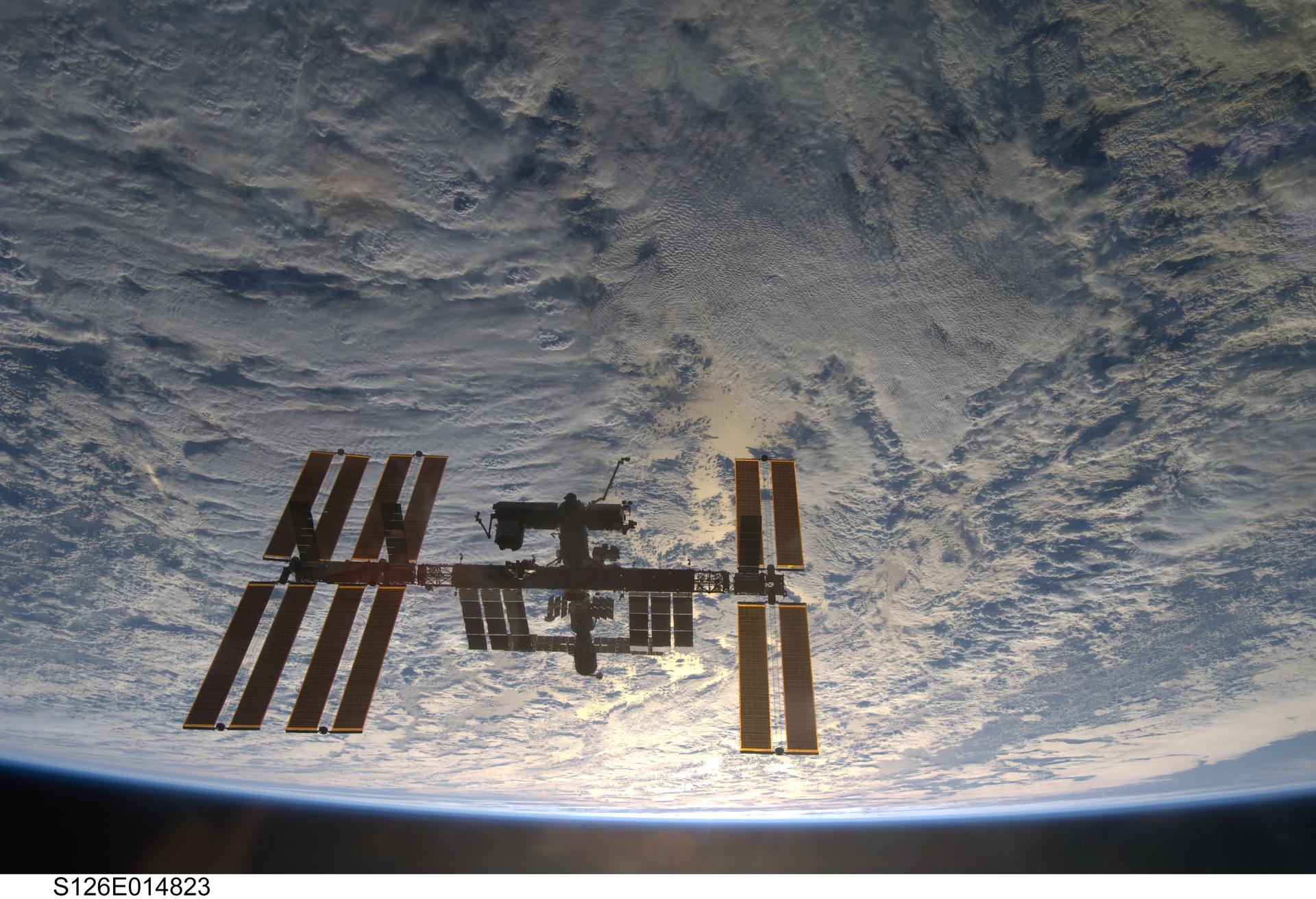 Backdropped by a cloud-covered part of Earth, the International Space Station is seen from Space Shuttle Endeavour as the two spacecraft begin their relative separation on Nov. 28, 2008.