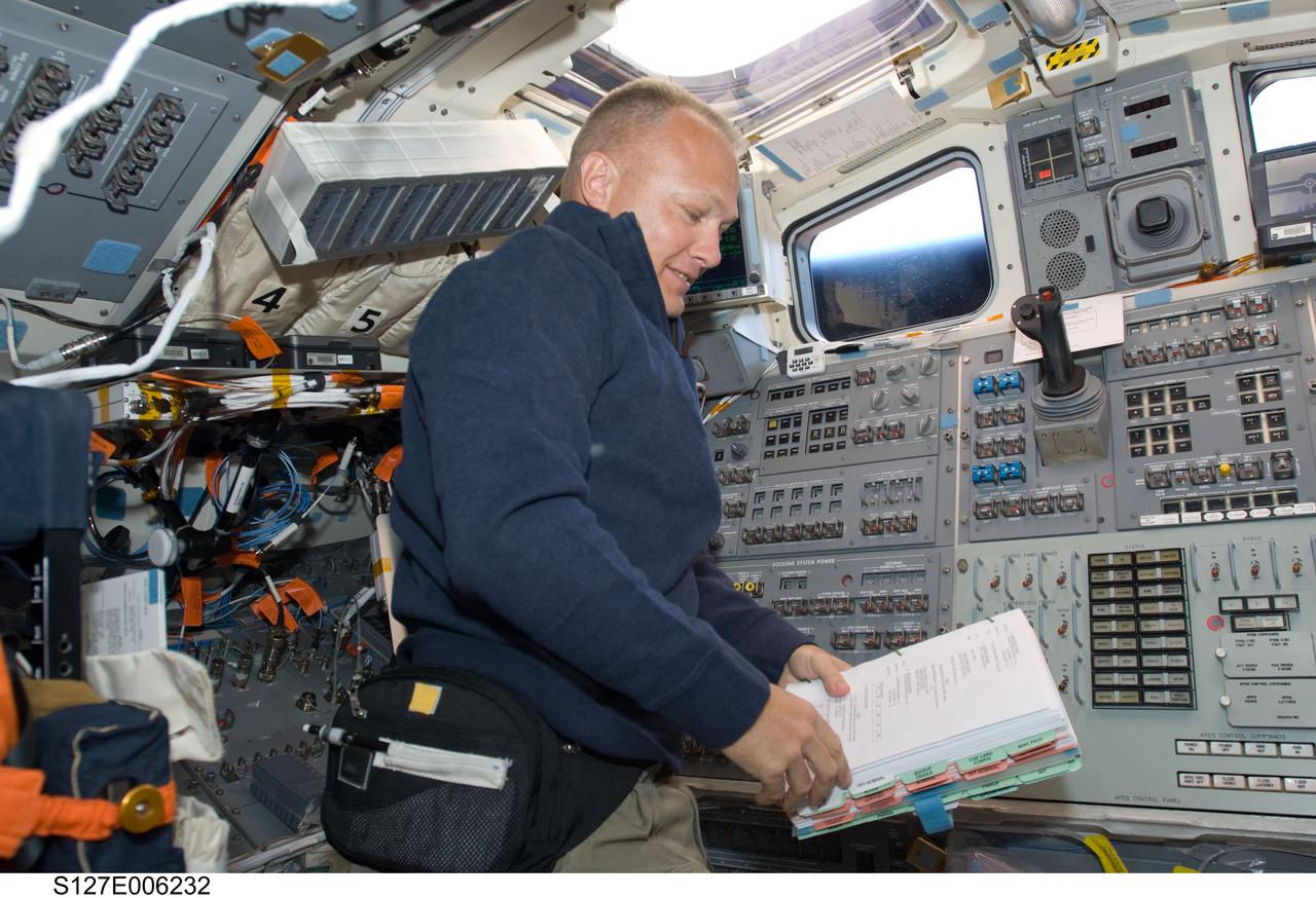 S127-E-006232 (16 July 2009) --- Astronaut Doug Hurley, STS-127 pilot, reads a checklist on the aft flight deck of Space Shuttle Endeavour during flight day two activities.