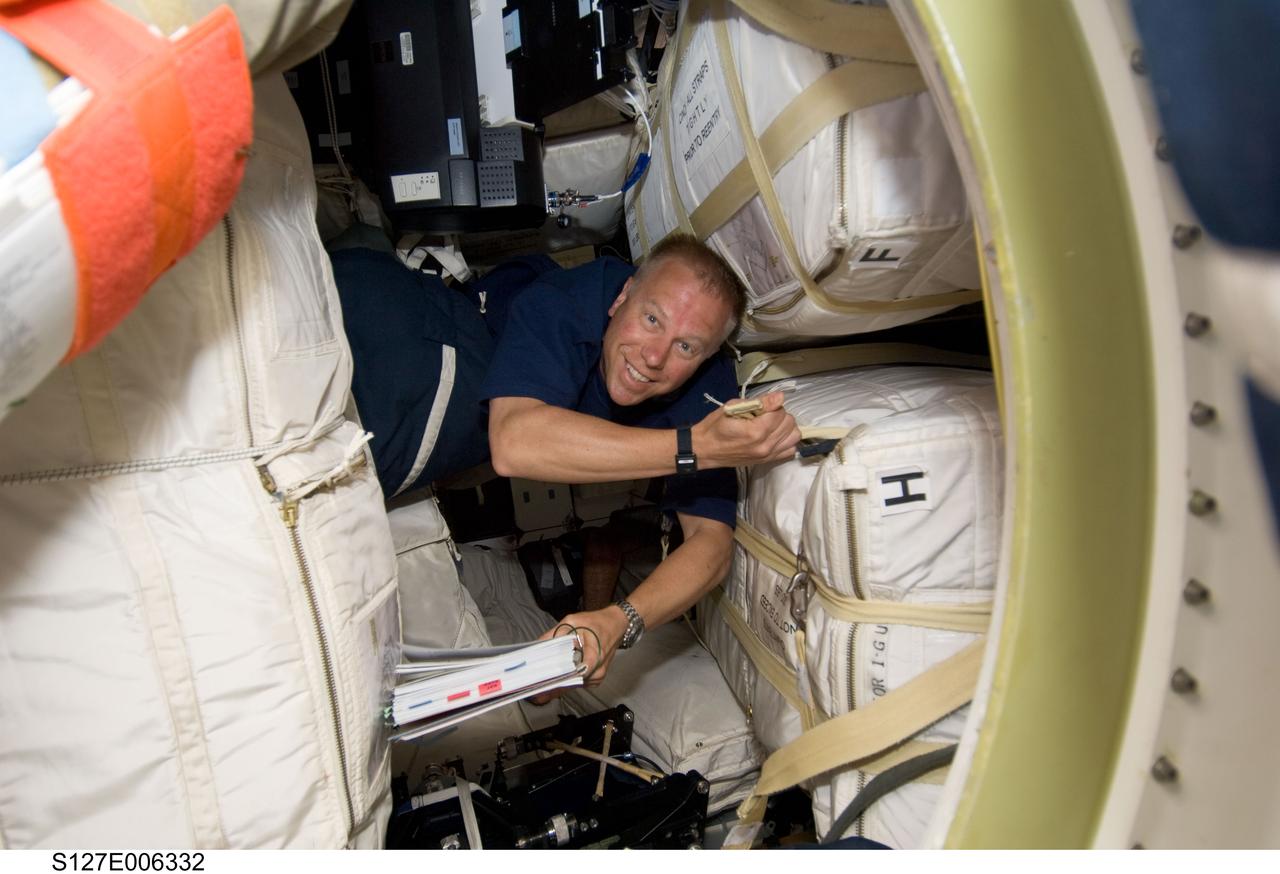 S127-E-006332 (16 July 2009) --- Astronaut Tim Kopra, STS-127 mission specialist, works among stowage containers on the middeck of Space Shuttle Endeavour during flight day two activities.