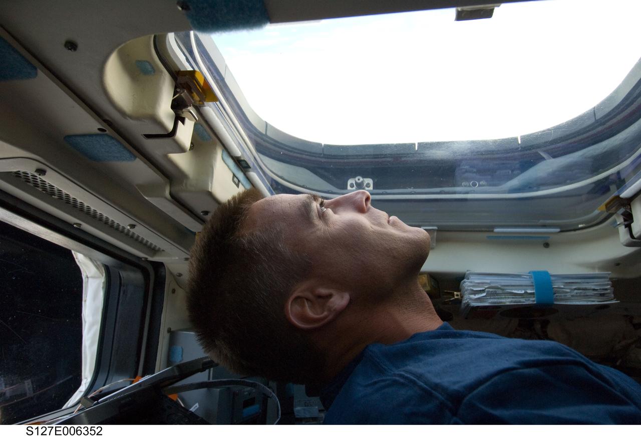 S127-E-006352 (16 July 2009) --- Astronaut Christopher Cassidy, STS-127 mission specialist, looks through an overhead window on the aft flight deck of Space Shuttle Endeavour during flight day two activities.