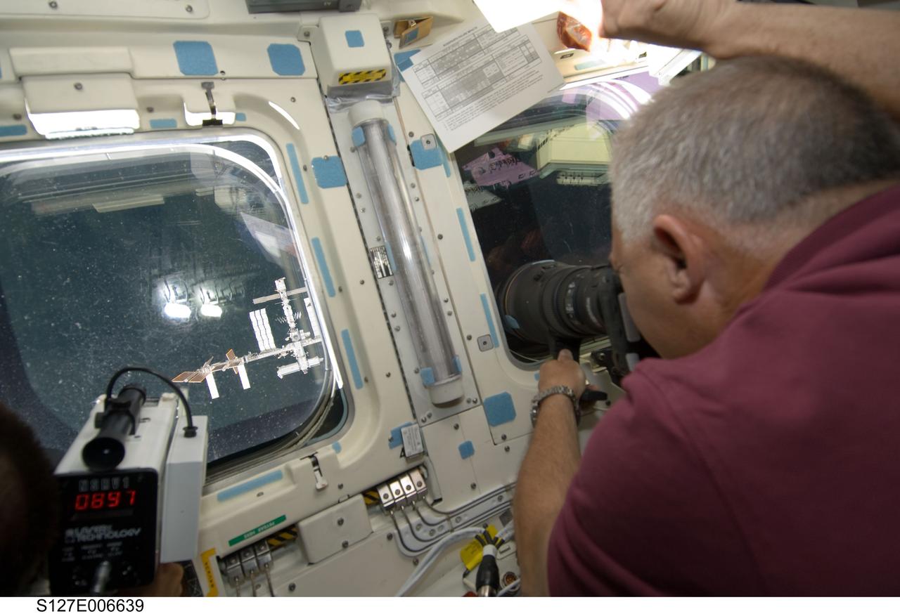 S127-E-006639 (17 July 2009) --- Onboard Endeavour's aft flight deck, astronaut Dave Wolf, STS-127 mission specialist, aims a camera at the International Space Station during rendezvous and docking activities on flight day three.
