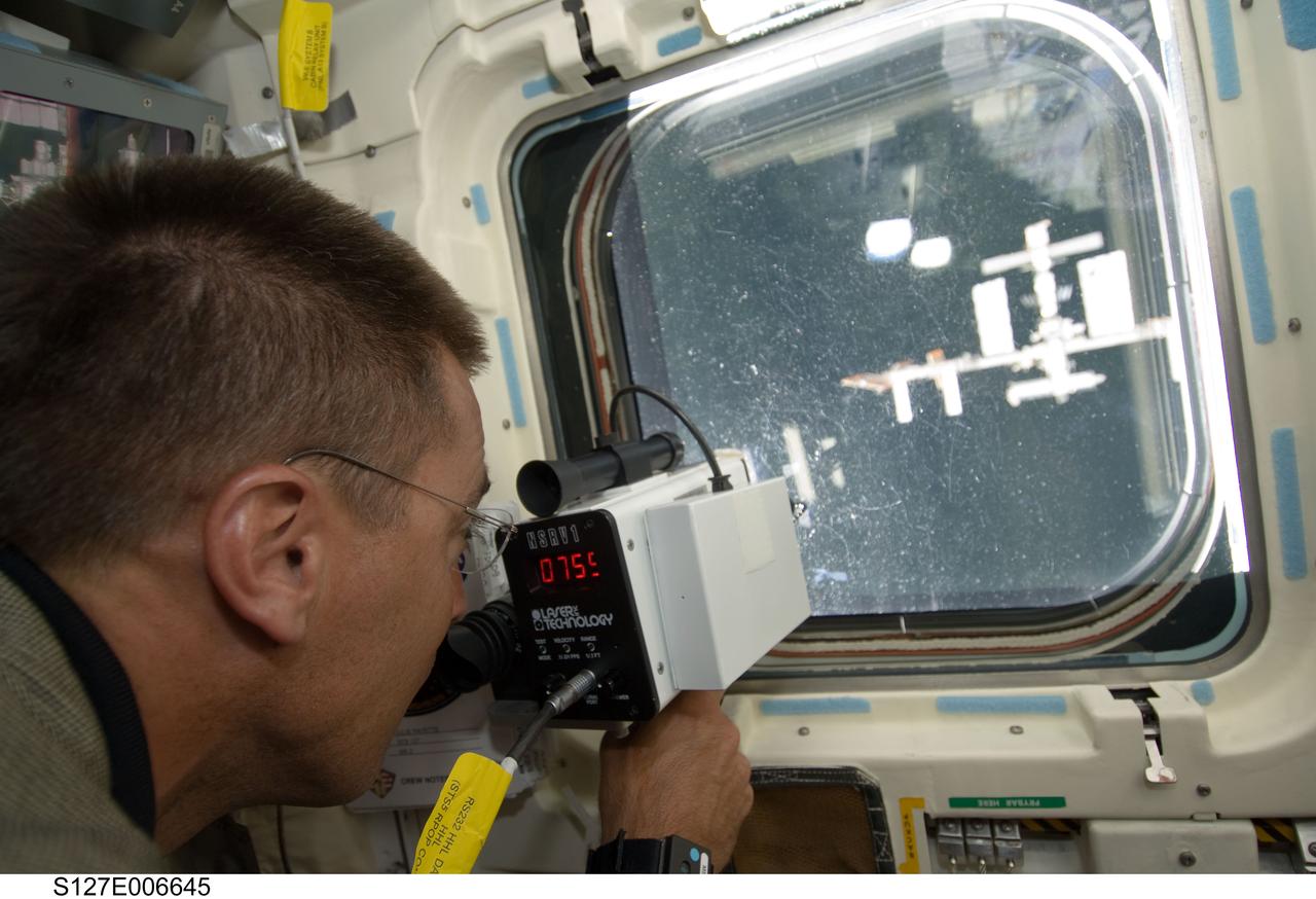 S127-E-006645 (17 July 2009) --- Astronaut Christopher Cassidy, STS-127 mission specialist, on Endeavour's flight deck, uses a range finding device to determine distance between the shuttle and the International Space Station during rendezvous and docking activities on flight day 3.