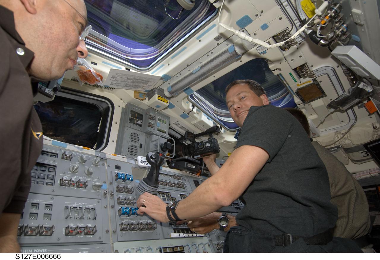 S127-E-006666 (17 July 2009) --- Astronaut Tom Marshburn, STS-127 mission specialist, positions a video camera in one of Endeavour's aft flight deck windows during flight day three activities.