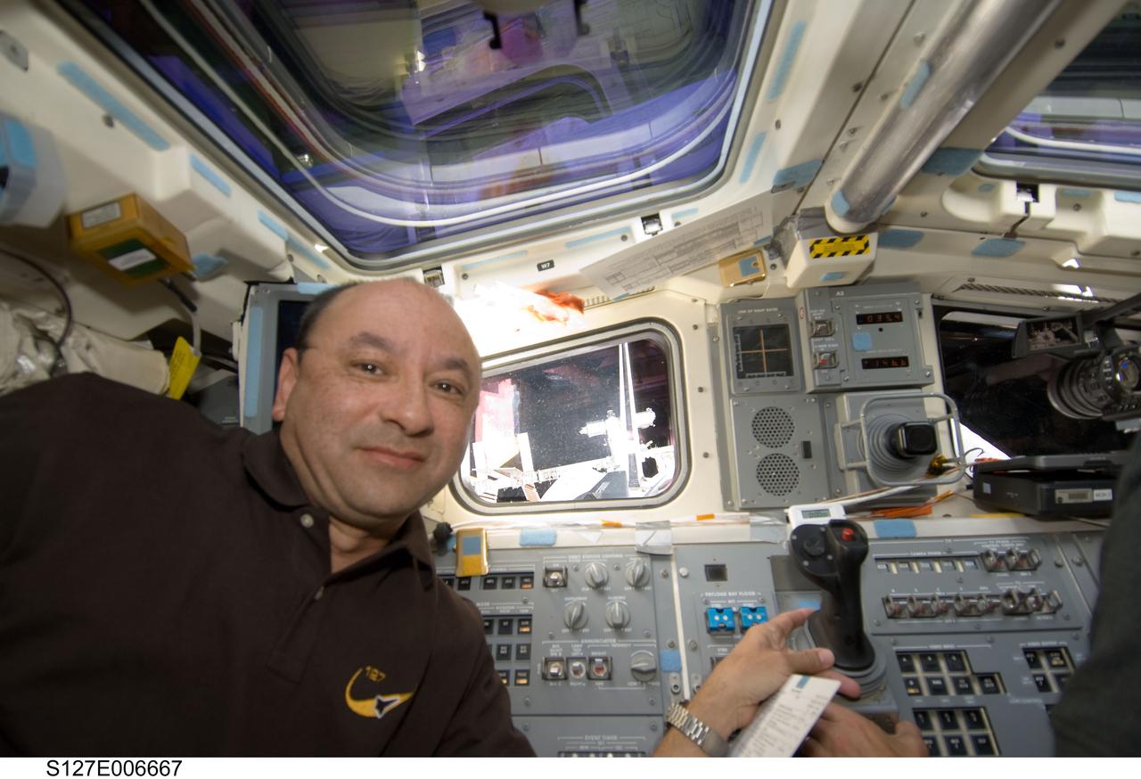 S127-E-006667 (17 July 2009) --- Astronaut Mark Polansky, STS-127 commander, stands near the aft flight deck controls of the Space Shuttle Endeavour during rendezvous and docking activities on flight day three. The International Space Station can be seen through the starboard window.