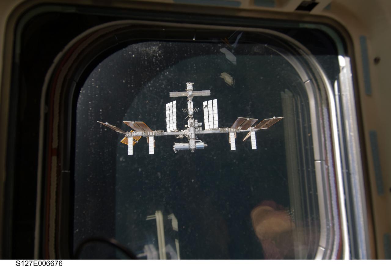 S127-E-006676 (17 July 2009) --- One of Endeavour's aft flight deck windows frames the nearby International Space Station as crewmembers aboard both spacecraft, totaling a record 13 human beings, anticipate over a week's worth of joint activities to bring the orbital outpost a step closer to completion.