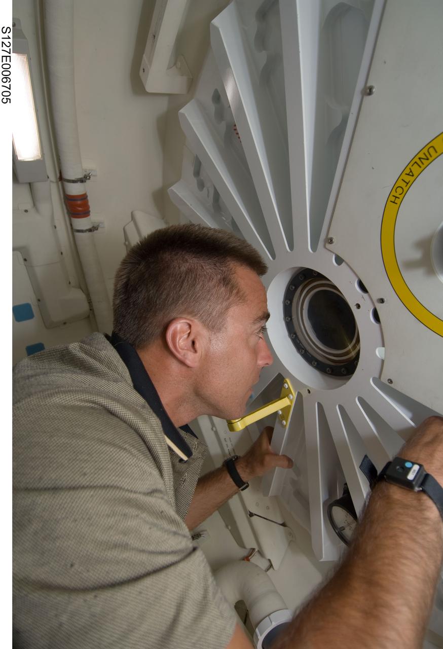 S127-E-006705 (17 July 2009) --- Astronaut Christopher Cassidy, STS-127 mission specialist, peers through a window in the hatch that separates seven Endeavour crew members from six International Space Station inhabitants. But the separation wasn't for long, as soon afterward the hatch was opened and the visitors from Earth moved onto the station to set the population record at 13. More importantly, over a week's worth of joint activities lies ahead for the two crews.