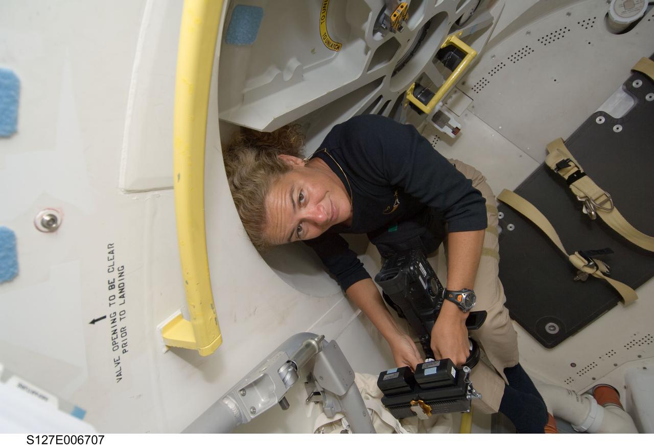 S127-E-006707 (17 July 2009) --- Canadian Space Agency astronaut Julie Payette, STS-127 mission specialist, stands by with a camera as she awaits the opening of the hatch that separates the STS-127 crew members from their hosts aboard the International Space Station.