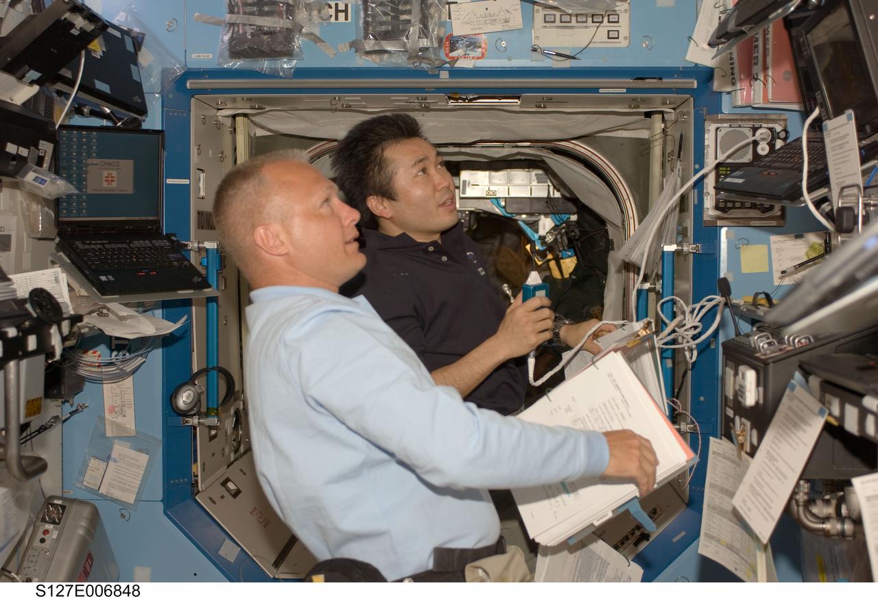 S127-E-006848 (18 July 2009) --- Japanese Aerospace Exploration Agency (JAXA) astronaut Koichi Wakata (right), Expedition 19/20 flight engineer, and astronaut Doug Hurley, STS-127 pilot, share intravehicular support to the first two spacewalkers who will be performing work on the International Space Station over the next week. When the Endeavour crew returns to Earth, Wakata will accompany it, having completed his current flight engineer duty during the STS-127 visit.