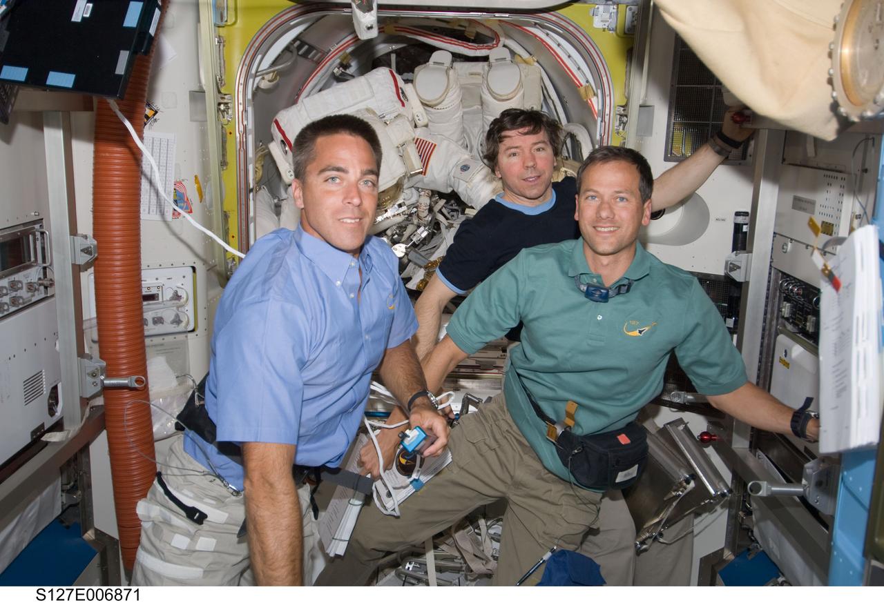 S127-E-006871 (18 July 2009) ---Two soon-to-be space-walking astronauts--Dave Wolf and Tim Kopra--although barely visible in the International Space Station's Quest airlock in the rear of this frame, are the primary focus of the three supportive astronauts in the foreground. From the left are astronauts Christopher Cassidy, Mike Barratt and Tom Marshburn. The July 18 extravehicular activity kicks off a series of five spacewalks scheduled over the next several days.