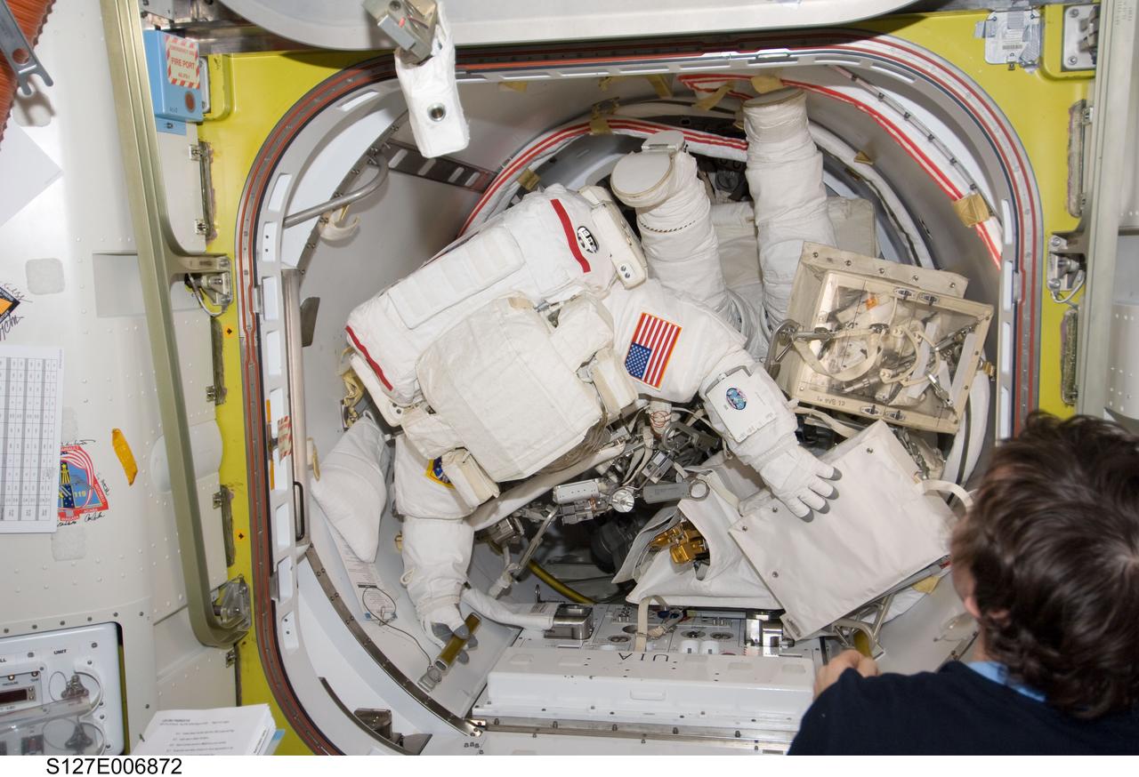 S127-E-006872 (18 July 2009) --- In the International Space Station's Quest airlock, astronauts Dave Wolf (foreground) and Tim Kopra (feet and legs visible in background) are suited and ready for the first of five spacewalks scheduled during the STS-127 mission.