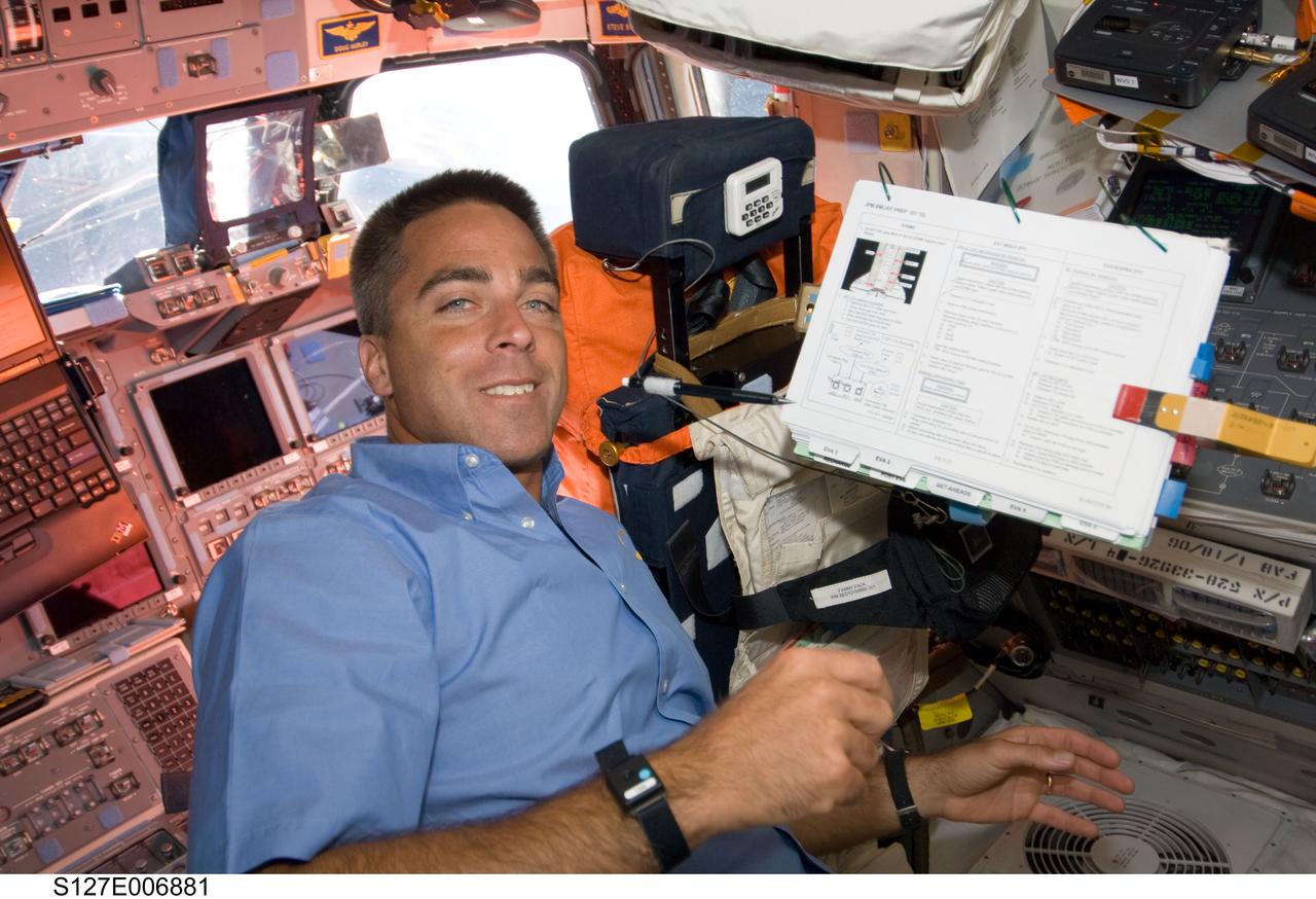 S127-E-006881 (18 July 2009) --- Onboard Endeavour's forward flight deck, astronaut Christopher Cassidy, STS-127 mission specialist, looks over a reference manual as he plays an intravehicular support role to two space-walking astronauts (Dave Wolf and Tim Kopra), out of frame.  The July 18 extravehicular activity kicks off a series of five spacewalks scheduled over the next several days.