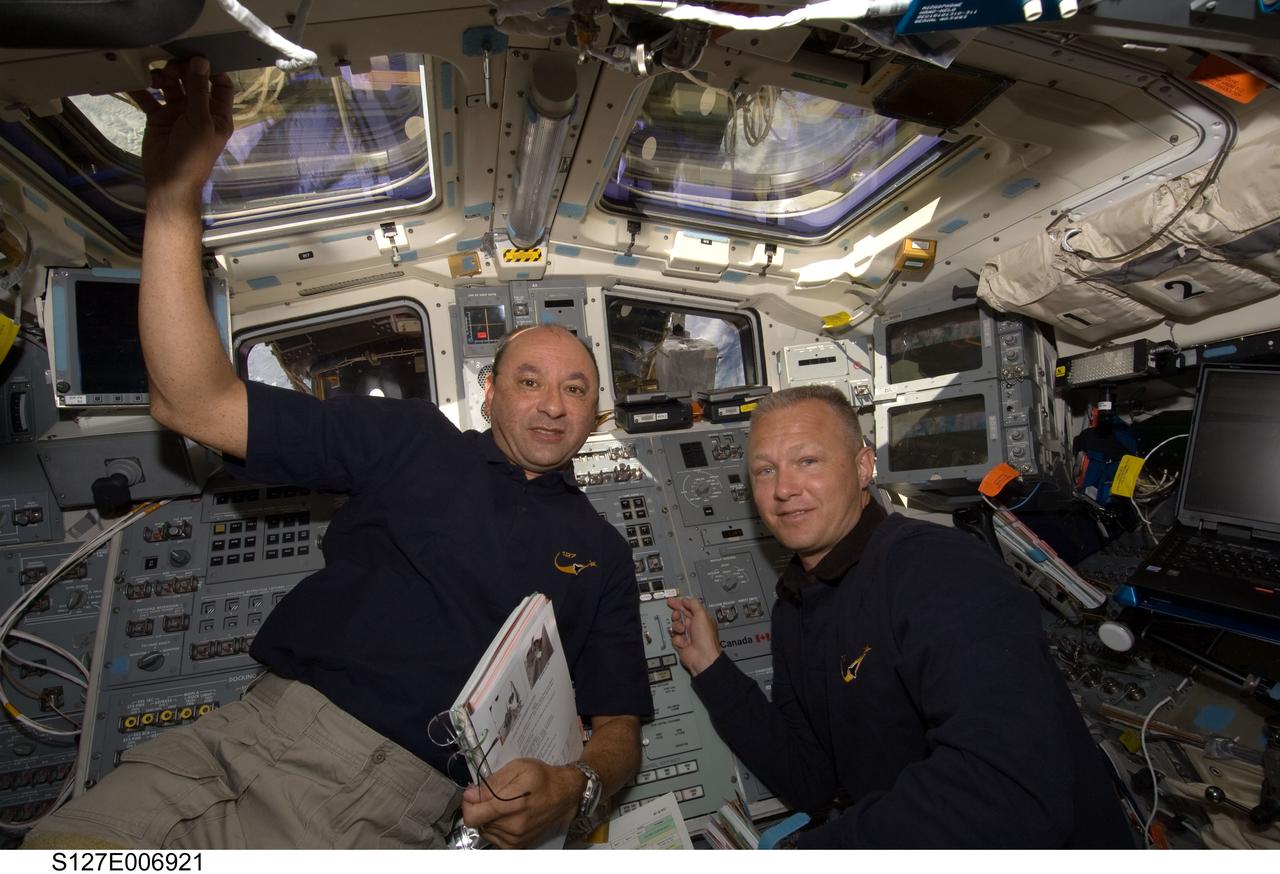 S127-E-006921 (19 July 2009) --- Astronauts Mark Polansky (left), commander, and Doug Hurley, pilot, are pictured at Endeavour's aft flight deck controls during flight day five operations with hardware on the International Space Station. The hardware moves will enable the second pair of spacewalkers--mission specialists Dave Wolf and Tom Marshburn--to perform its spacewalk assignment on July 20.