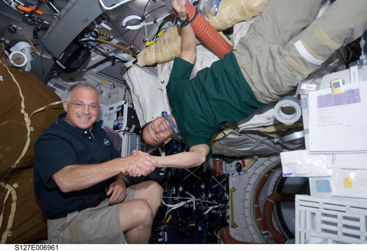 S127-E-006961 (19 July 2009) --- Astronauts Dave Wolf (left) and Tom Marshburn, both STS-127 mission specialists, share a moment shaking hands on the mid deck of the Space Shuttle Endeavour. Tomorrow they will share more than a few moments performing a spacewalk to perform work on the adjoined International Space Station.