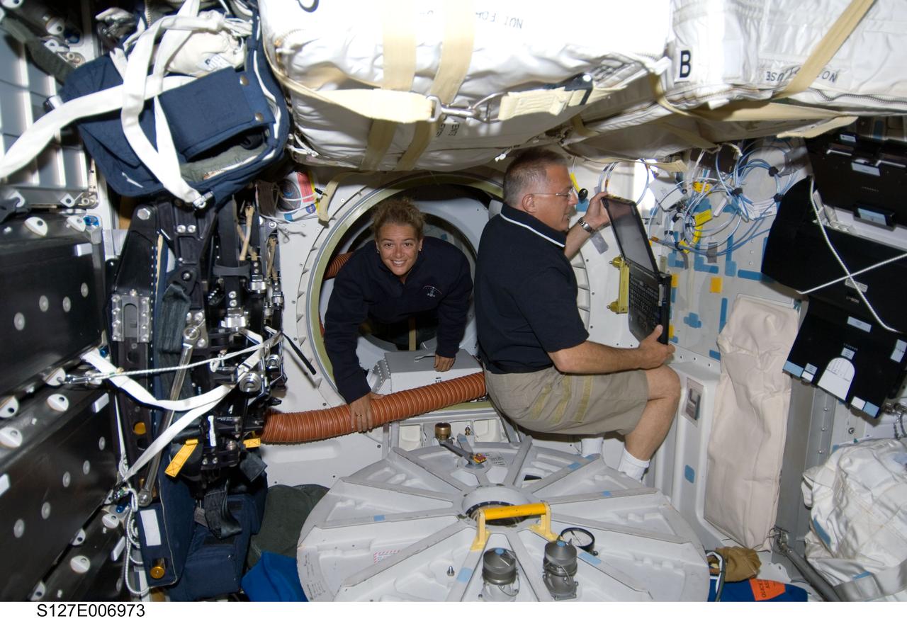 S127-E-006973 (19 July 2009) --- Canadian Space Agency astronaut Julie Payette floats onto the middeck of the Space Shuttle Endeavour, where she joins astronaut Dave Wolf, who makes an entry on a laptop computer.  The two STS-127 mission specialists are part of a seven member shuttle crew currently visiting the International Space Station, which is now docked with the shuttle.