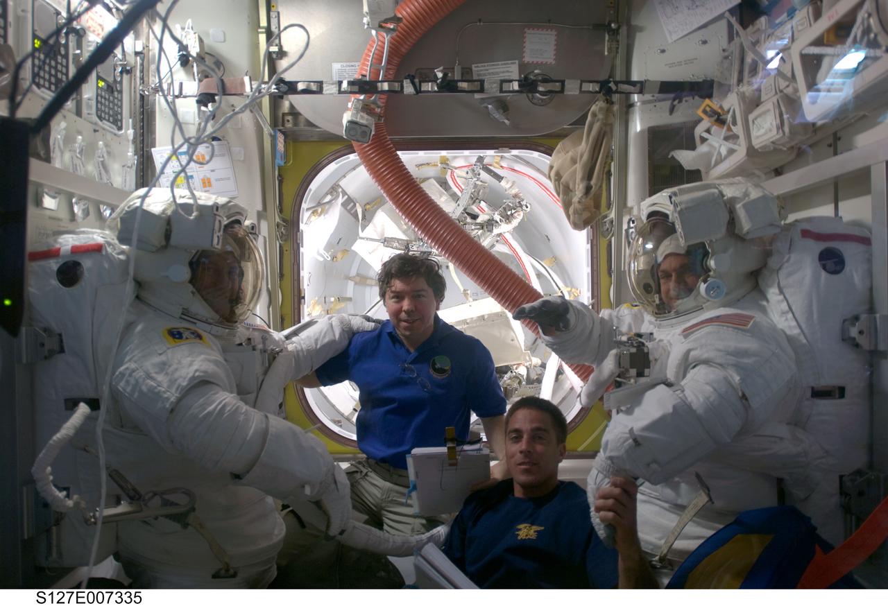 S127-E-007335 (20 July 2009) --- Two members of the flight day six spacewalk crew--the second one of five scheduled for the joint aggregation of shuttle and space station crewmembers--go through the final touches on the donning of their spacesuits prior to egressing the joint airlock of the orbital outpost. Suited astronauts Dave Wolf (left) and Tom Marshburn (right)are assisted by astronauts Mike Barratt (center frame), Expedition 20 flight engineer, and Christopher Cassidy (bottom), STS-127 mission specialist.