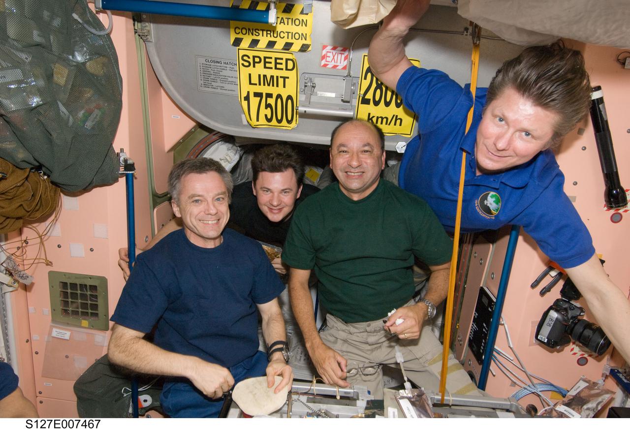 S127-E-007467 (21 July 2009) --- As dinner is served onboard the International Space Station, many of the 13 current habitants begin to come in for a serving. From left to right are Canadian Space Agency astronaut Robert Thirsk, Russian Federal Space Agency cosmonaut Roman Romanenko, astronaut Mark Polansky and cosmonaut Gennady Padalka. Polansky and Padalka are commanders for the station and shuttle crews, respectively.