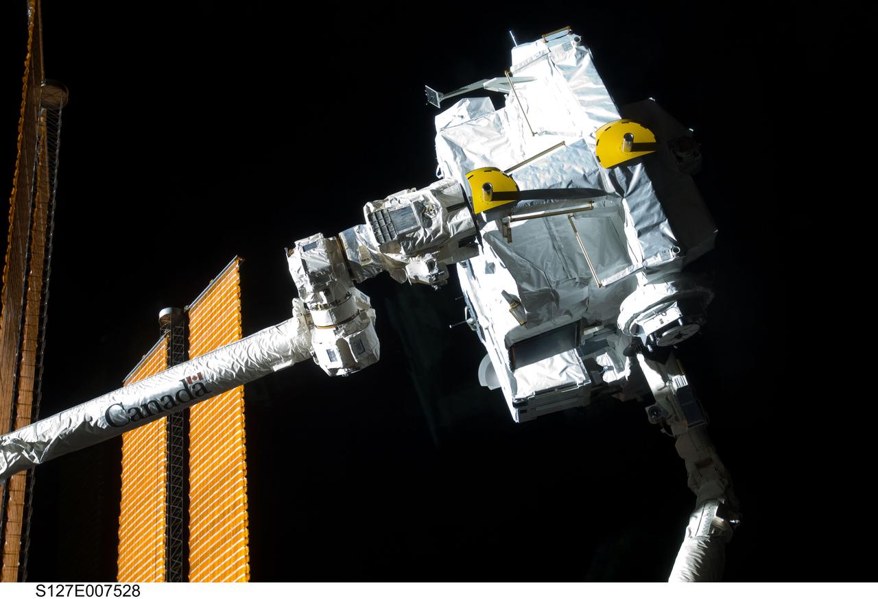 S127-E-007528 (21 July 2009) --- The Japanese Logistics Module – Exposed Section (JLE) is handed over from Endeavour's remote manipulator system to the space station's remote manipulator system (Canadarm2) during JLE unberthing and mating operations on flight day seven.