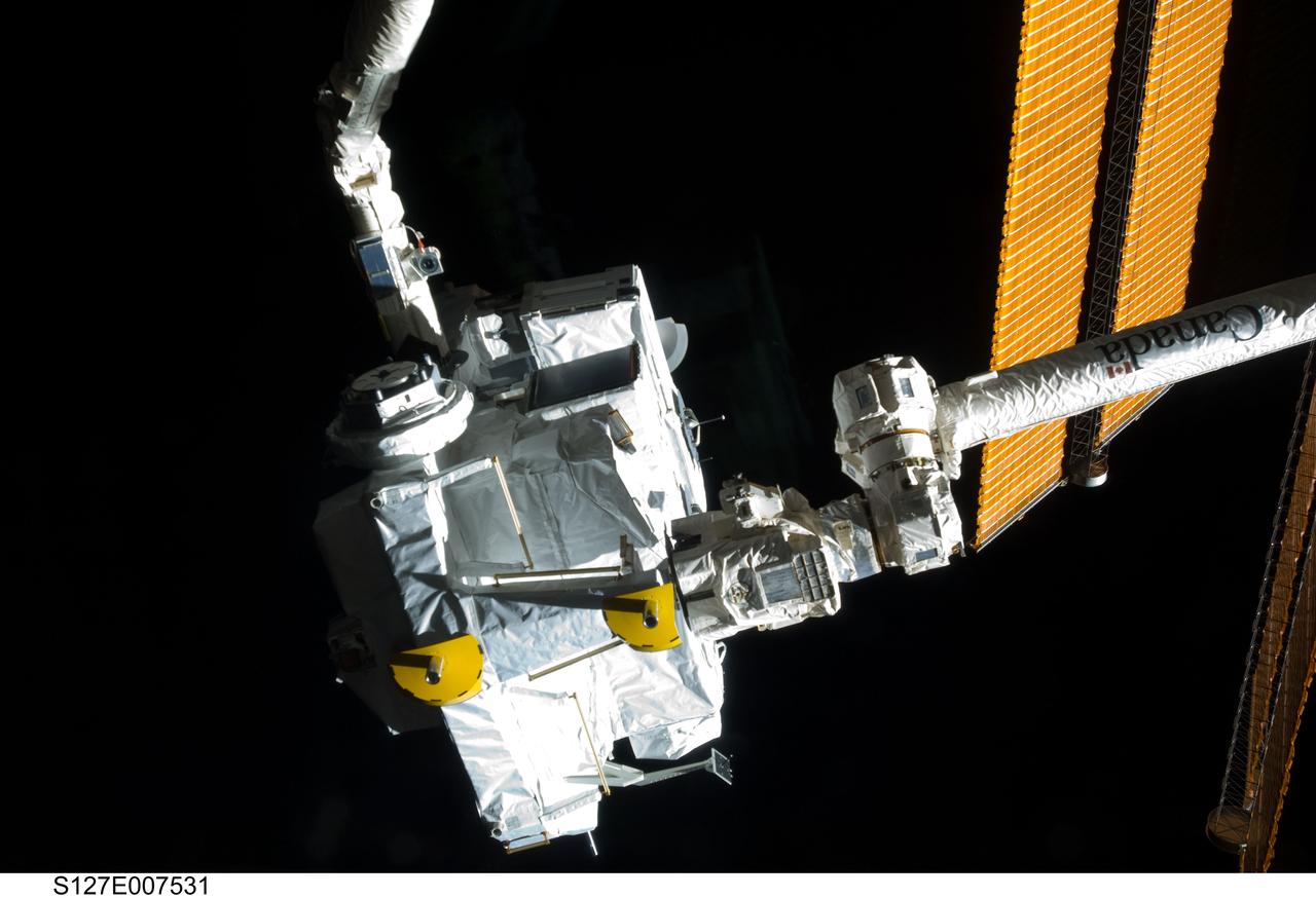 S127-E-007531 (21 July 2009) --- The Japanese Logistics Module – Exposed Section (JLE) is handed over from Endeavour's remote manipulator system to the space station's remote manipulator system (Canadarm2) during JLE unberthing and mating operations on flight day seven.