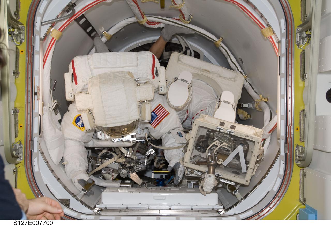 S127-E-007700 (22 July 2009) --- Astronaut Dave Wolf, STS-127 mission specialist, is seconds away from egressing the International Space Station to begin his third spacewalk of the current mission. Astronaut Christopher Cassidy, mission specialist, whose feet and backpack are visible, was about to make his initial spacewalk.