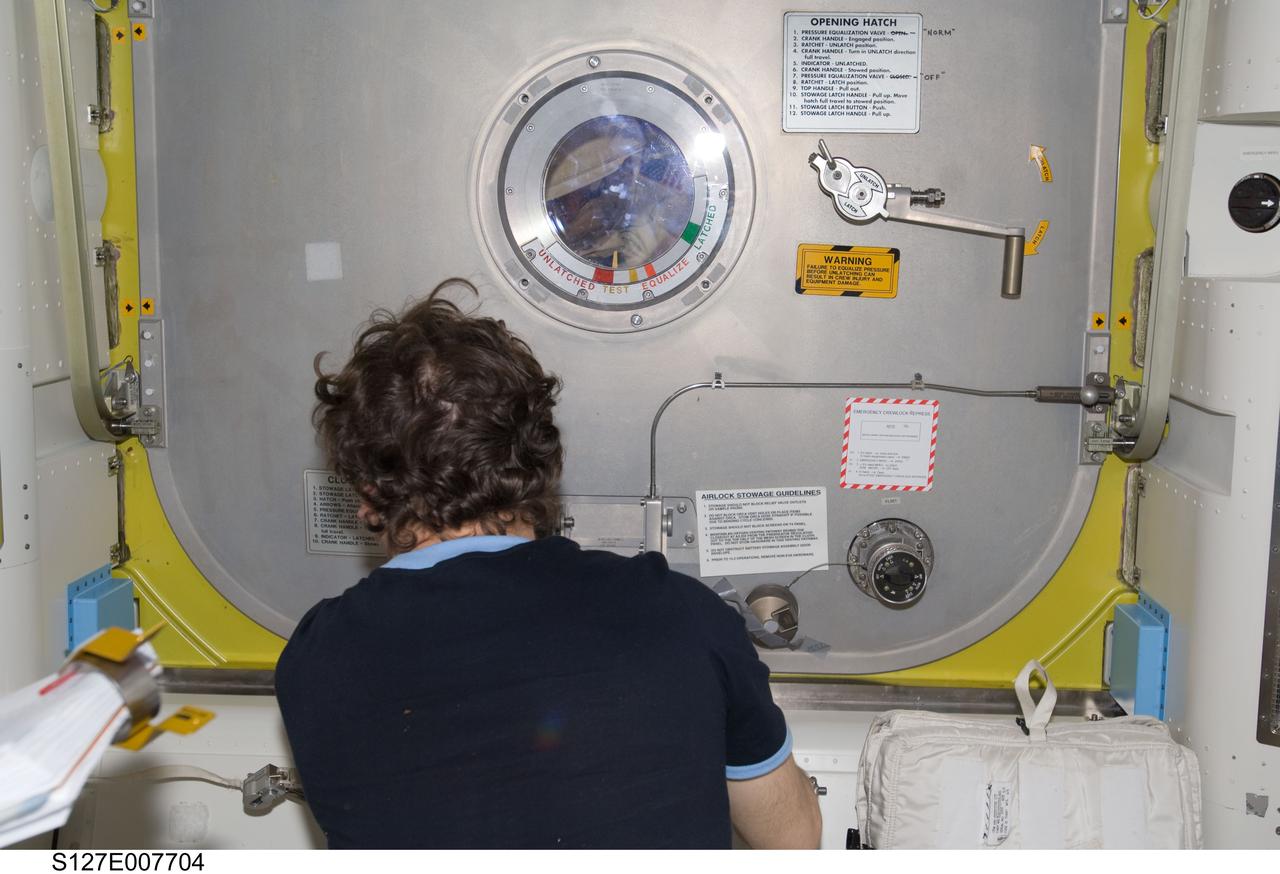 S127-E-007704 (22 July 2009) --- Astronaut Mike Barratt, Expedition 20 flight engineer, looks at astronaut Dave Wolf through the hatch window just after "sending off" astronauts Wolf and Christopher Cassidy (out of frame) for Endeavour's third space walk of a scheduled five overall for this flight.
