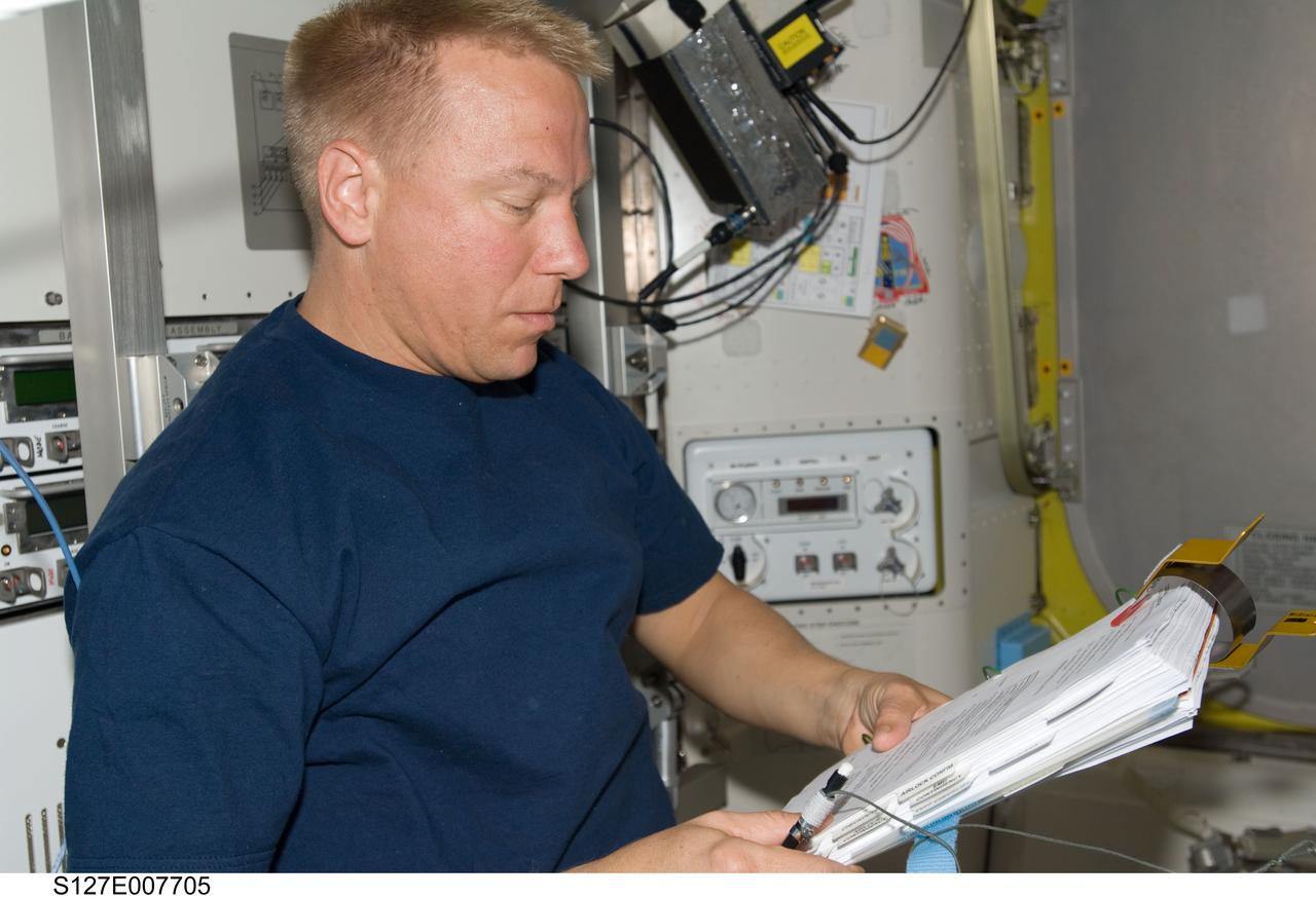 S127-E-007705 (22 July 2009) --- Astronaut Tim Kopra, Expedition 20 flight engineer, looks over a checklist while assisting the spacewalk preparations of astronauts Dave Wolf and Christopher Cassidy (both out of frame) onboard the International Space Station. This was the third of five scheduled sessions of extravehicular activity to continue work on the orbital outpost.