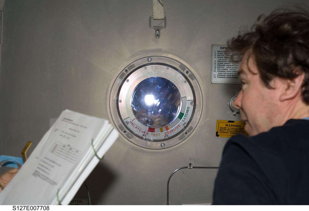 S127-E-007708 (22 July 2009) --- Astronaut Mike Barratt, Expedition 20 flight engineer, looks at astronaut Dave Wolf through the hatch window just after "sending off" astronauts Wolf and Christopher Cassidy (out of frame) for Endeavour's third space walk of a scheduled five overall for this flight.