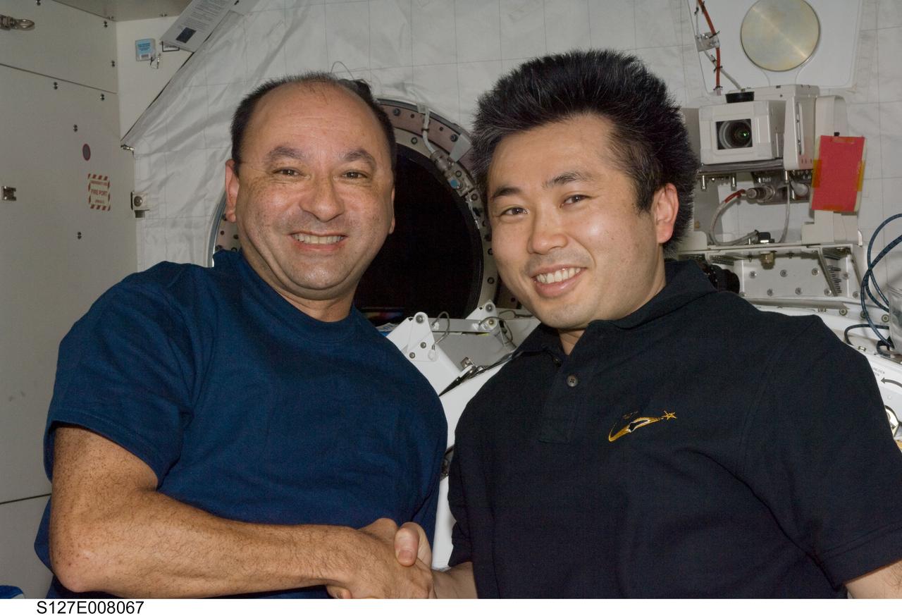 S127-E-008067 (23 July 2009)--- Inside Kibo or the Japanese Experiment Module (JEM), astronaut Mark Polansky (left), STS-127 commander, shakes hands with Japanese Aerospace Exploration Agency astronaut Koichi Wakata, who has been onboard the International Space Station for a tour of duty as flight engineer but will be returning to Earth with Polansky and the rest of the STS-127 crew next week.
