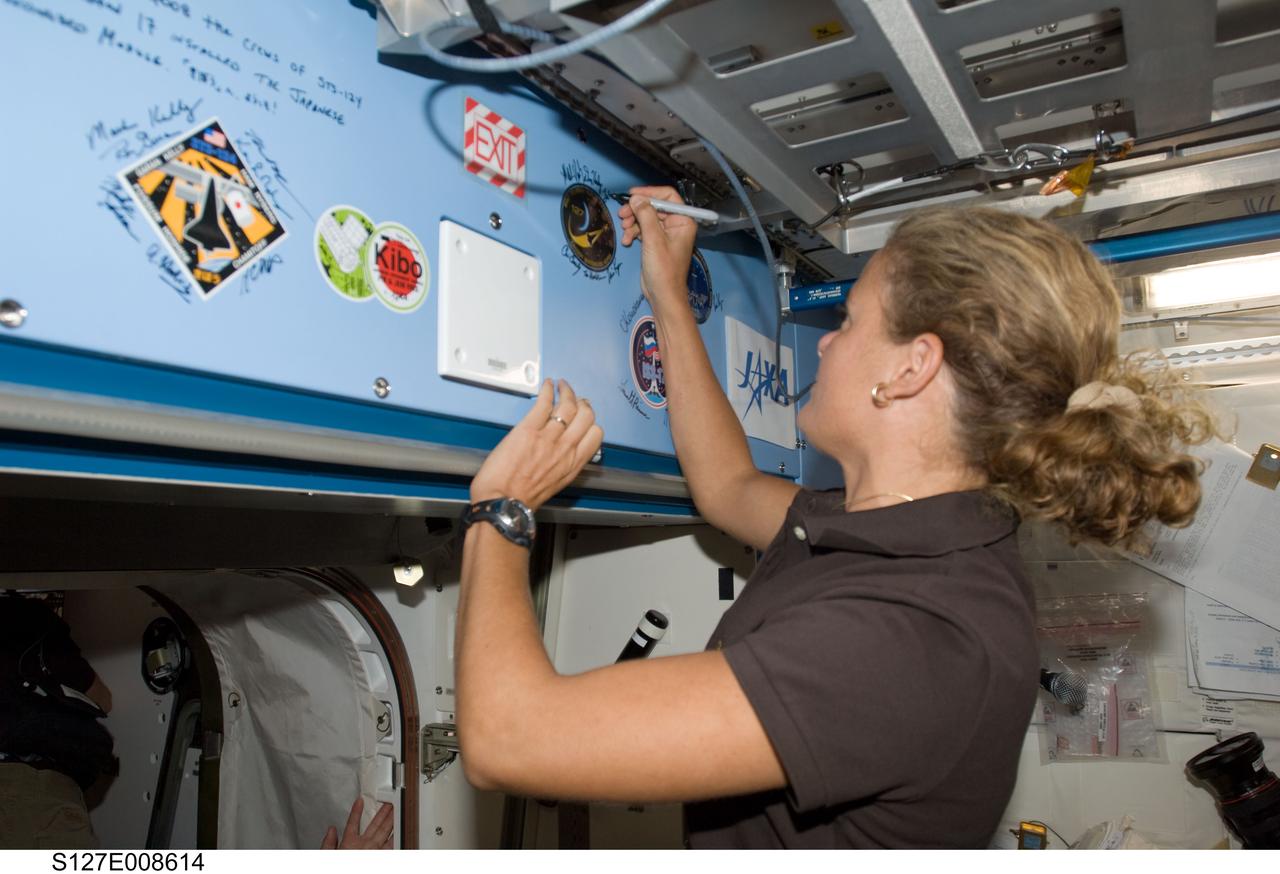 S127-E-008614 (25 July 2009) --- Flight day 11 activities for the joint shuttle-station crews included the traditional autographing of the station. Canadian Space Agency astronaut Julie Payette, STS-127 mission specialist, has the pen in this frame.