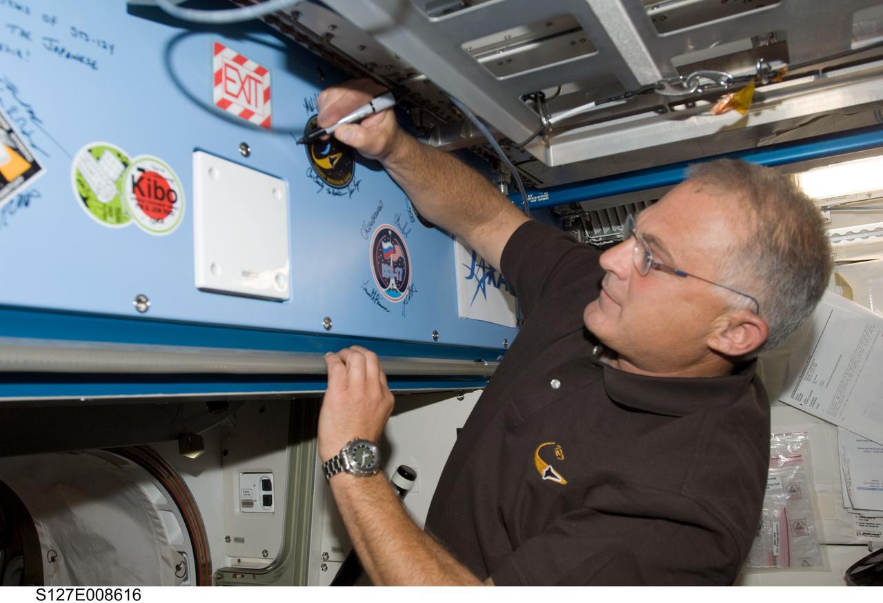 S127-E-008616 (25 July 2009) --- Flight day 11 activities for the joint shuttle-station crews included the traditional autographing of the station. Astronaut Dave Wolf, STS-127 mission specialist, has the pen in this frame.