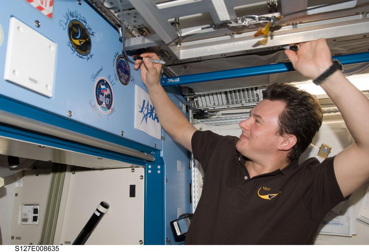 S127-E-008635 (25 July 2009) --- Flight day 11 activities for the joint shuttle-station crews included the traditional autographing of the station. Russian Federal Space Agency cosmonaut Roman Romanenko, Expedition 20 flight engineer,  has the pen in this frame.