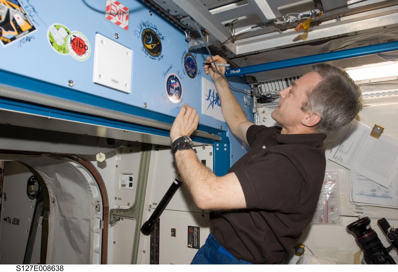 S127-E-008638 (25 July 2009) --- Flight day 11 activities for the joint shuttle-station crews included the traditional autographing of the station. Canadian Space Agency astronaut Robert Thirsk, Expedition 20 flight engineer,  has the pen in this frame.