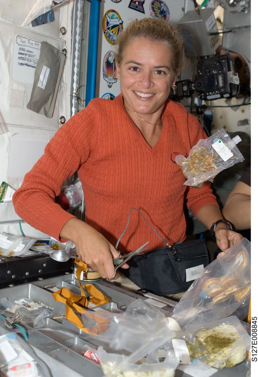 S127-E-008845 (25 July 2009) --- Canadian Space Agency astronaut Julie Payette, STS-127 mission specialist, is pictured near a food package floating freely in the Unity node of the International Space Station while Space Shuttle Endeavour remains docked with the station.
