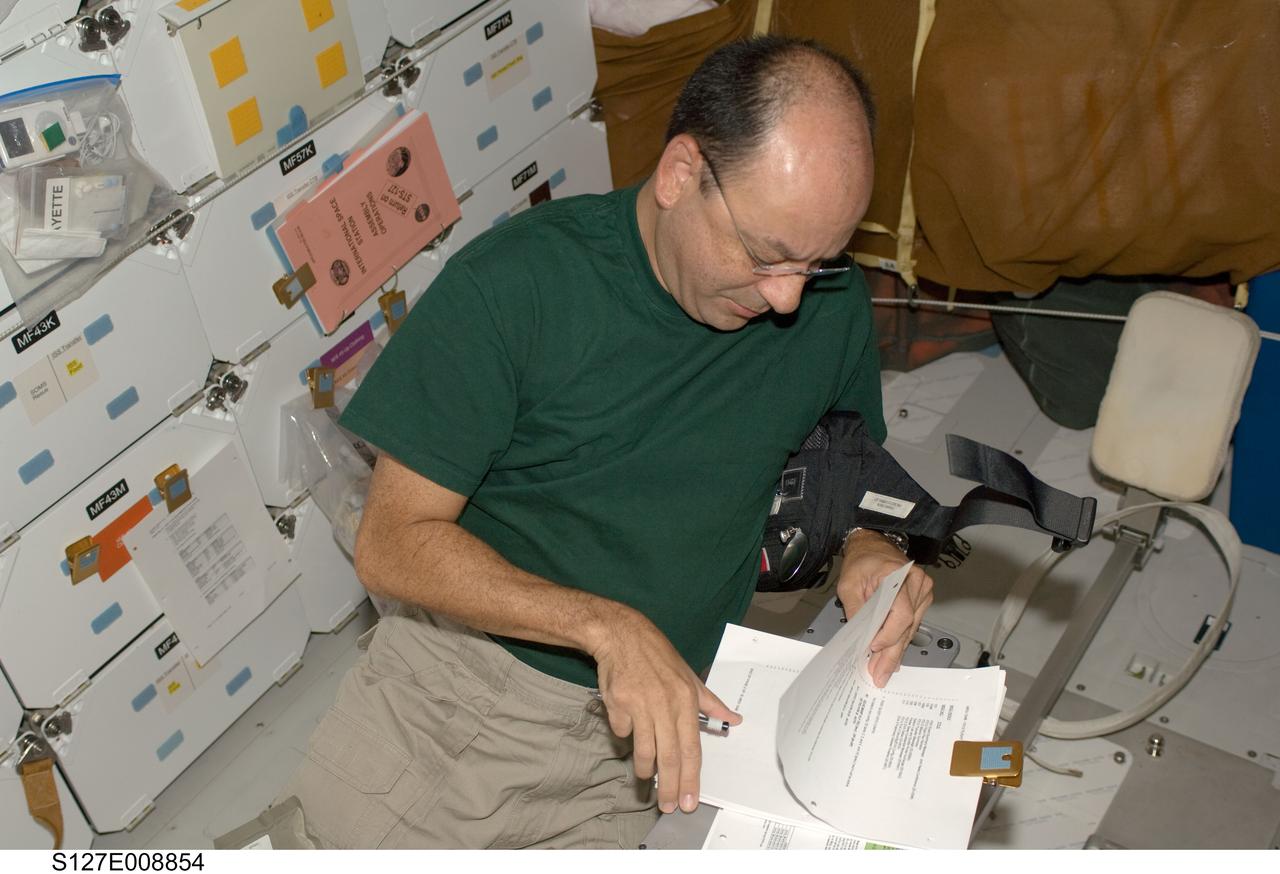 S127-E-008854 (26 July 2009) --- Astronaut Mark Polansky, STS-127 commander,  looks over checklists on the middeck of Space Shuttle Endeavour while docked with the International Space Station.
