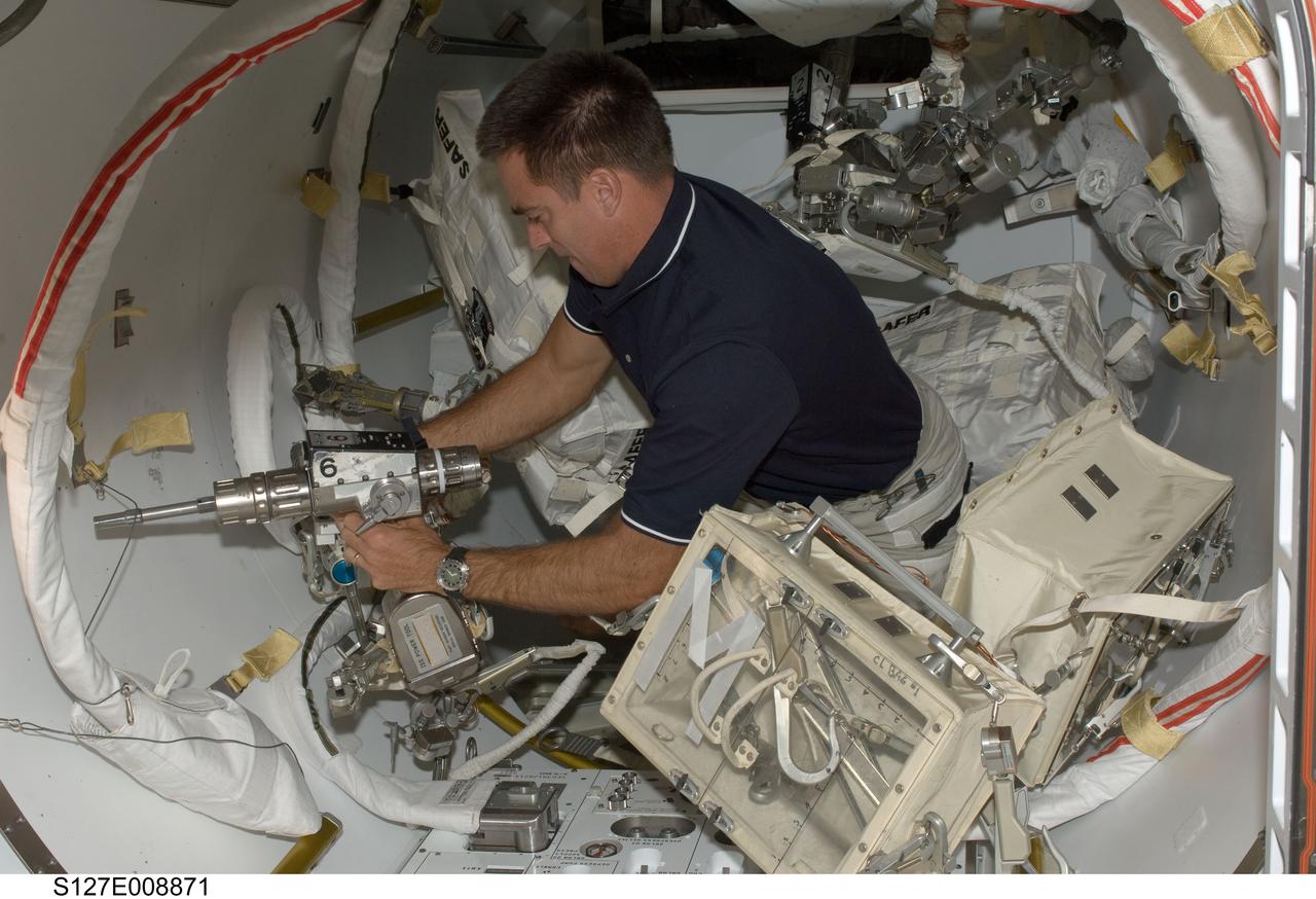S127-E-008871 (26 July 2009) --- Astronaut Christopher Cassidy, STS-127 mission specialist, works with extravehicular activity (EVA) tools in the Quest airlock of the International Space Station while Space Shuttle Endeavour remains docked with the station.