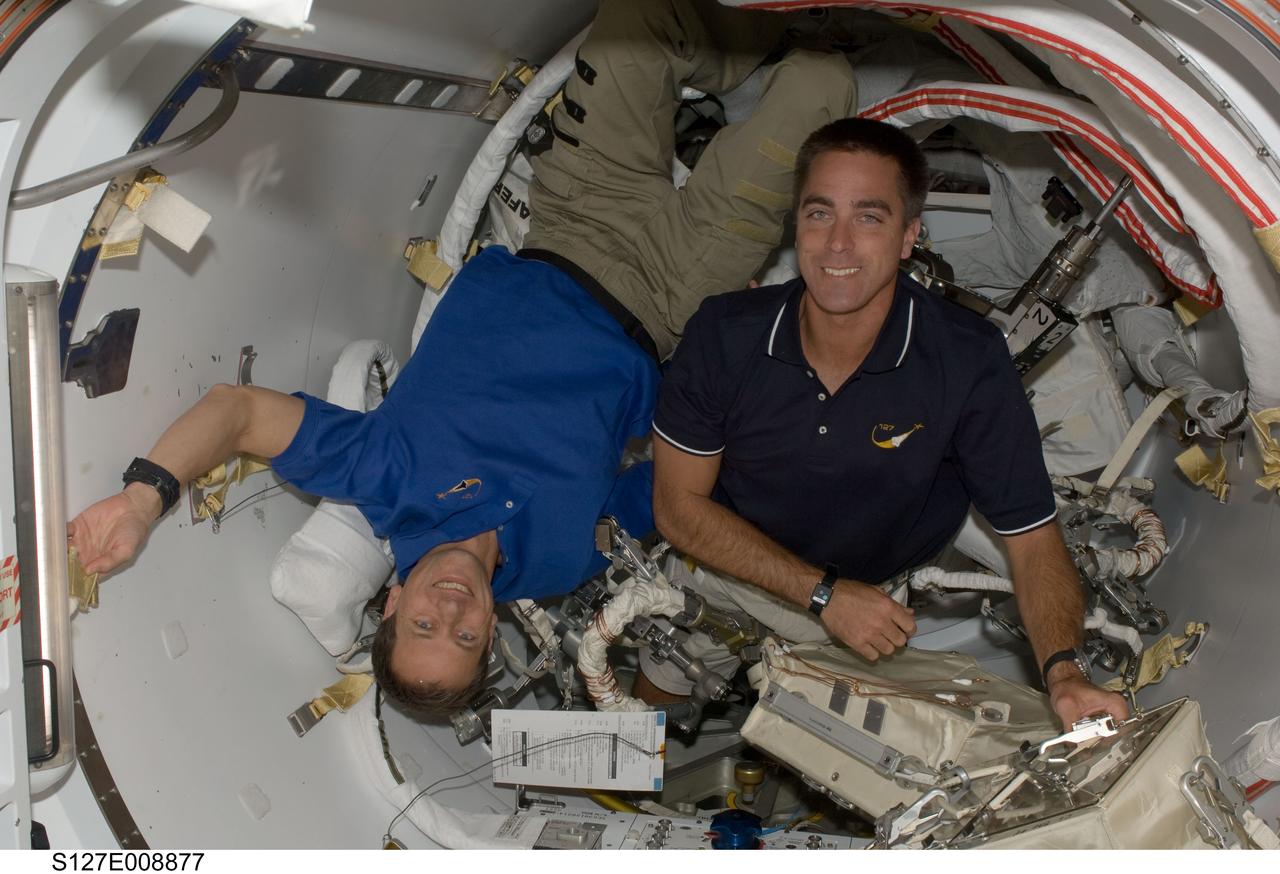 S127-E-008877 (26 July 2009) --- Astronauts Tom Marshburn (left) and Christopher Cassidy, both STS-127 mission specialists, work with extravehicular activity (EVA) tools in the Quest airlock of the International Space Station while Space Shuttle Endeavour remains docked with the station.