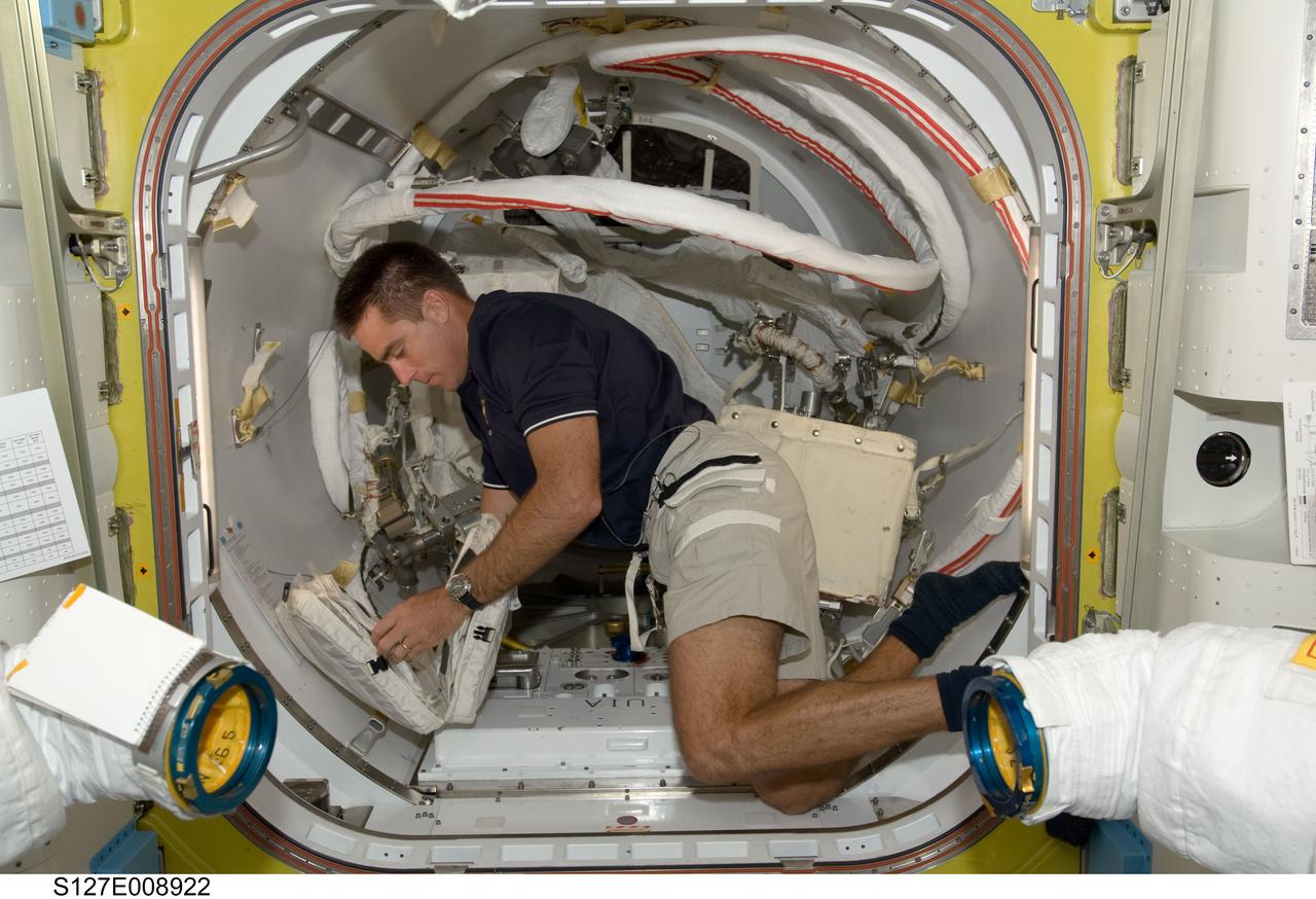 S127-E-008922 (26 July 2009) --- Astronaut Christopher Cassidy, STS-127 mission specialist, works with extravehicular activity (EVA) equipment in the Quest airlock of the International Space Station while Space Shuttle Endeavour remains docked with the station.