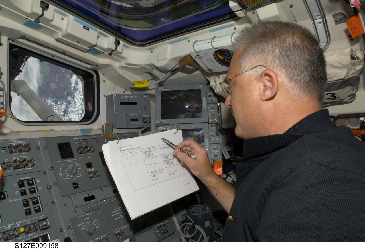 S127-E-009158 (27 July 2009) --- Astronaut Dave Wolf, STS-127 mission specialist, looks over a checklist on the aft flight deck of Space Shuttle Endeavour while docked with the International Space Station.