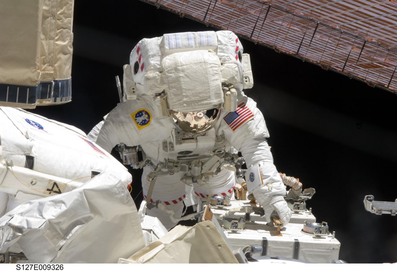 S127-E-009326 (27 July 2009) --- Astronauts Christopher Cassidy and Tom Marshburn (mostly out of frame at left), both STS-127 mission specialists, participate in the mission's fifth and final session of extravehicular activity (EVA) as construction and maintenance continue on the International Space Station. During the four-hour, 54-minute spacewalk, Marshburn and Cassidy secured multi-layer insulation around the Special Purpose Dexterous Manipulator known as Dextre, split out power channels for two space station Control Moment Gyroscopes, installed video cameras on the front and back of the new Japanese Exposed Facility and performed a number of “get ahead” tasks, including tying down some cables and installing handrails and a portable foot restraint to aid future spacewalkers.