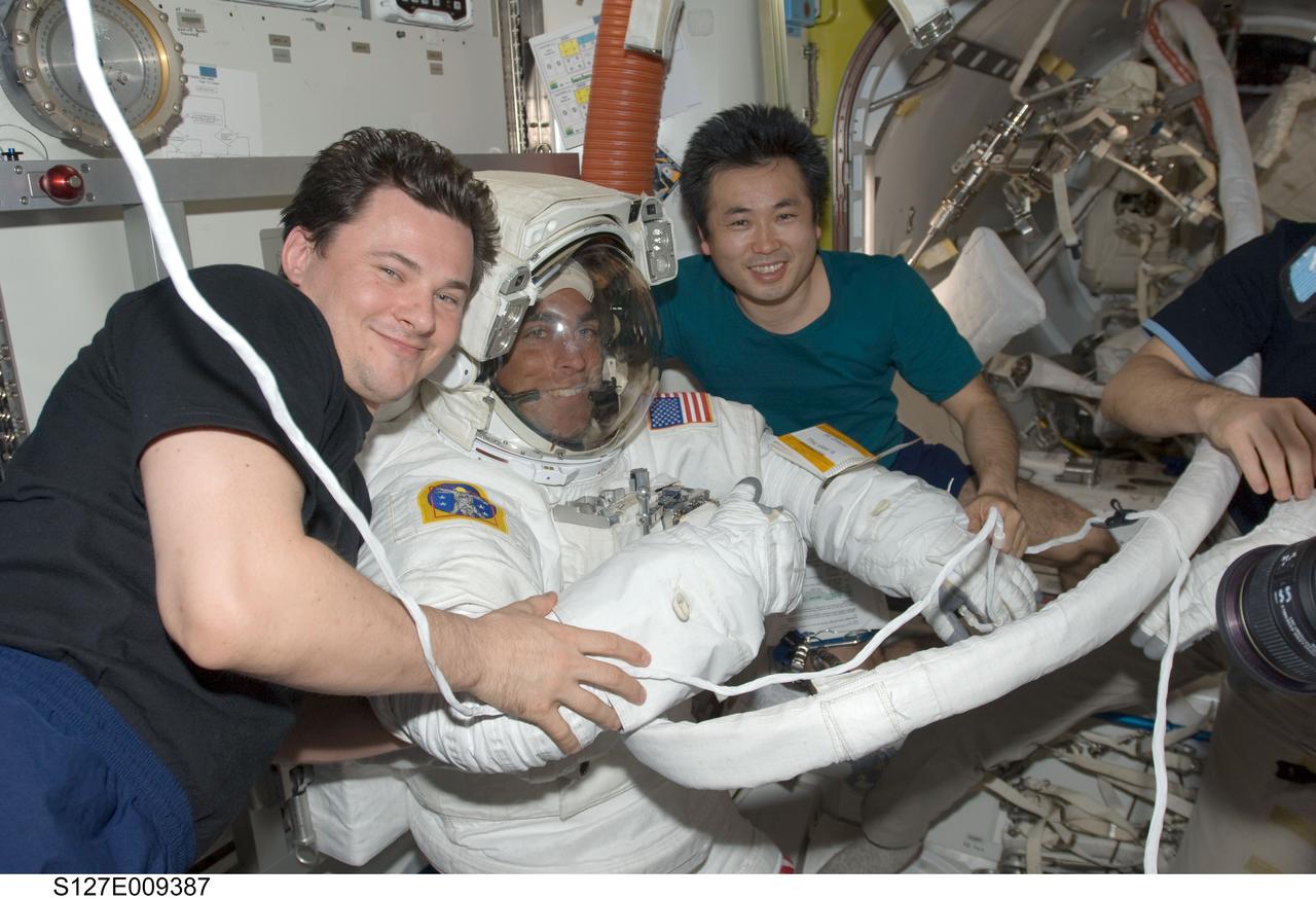 S127-E-009387 (27 July 2009) --- Attired in his Extravehicular Mobility Unit (EMU) spacesuit, astronaut Christopher Cassidy, STS-127 mission specialist, is pictured in the Quest Airlock of the International Space Station as the mission's fifth and final session of extravehicular activity (EVA) draws to a close. Cosmonaut Roman Romanenko (left), Expedition 20 flight engineer; and Japan Aerospace Exploration Agency (JAXA) astronaut Koichi Wakata, mission specialist, assist with the doffing of the spacesuit.