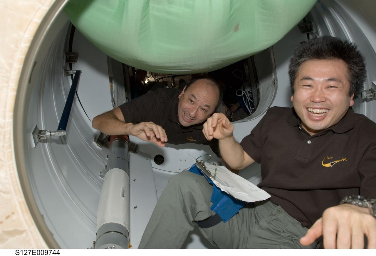 S127-E-009744 (28 July 2009) --- NASA astronaut Mark Polansky (background), STS-127 commander; and Japan Aerospace Exploration Agency (JAXA) astronaut Koichi Wakata, mission specialist, work in the hatch between Space Shuttle Endeavour and the International Space Station as they prepare for the undocking of the two spacecraft.