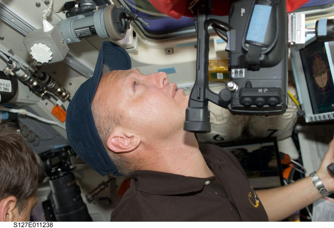 S127-E-011238 (28 July 2009) --- Astronaut Doug Hurley, STS-127 pilot, uses a High Definition Video (HDV) camera at an overhead window on the aft flight deck of Space Shuttle Endeavour during flight day 14 activities.