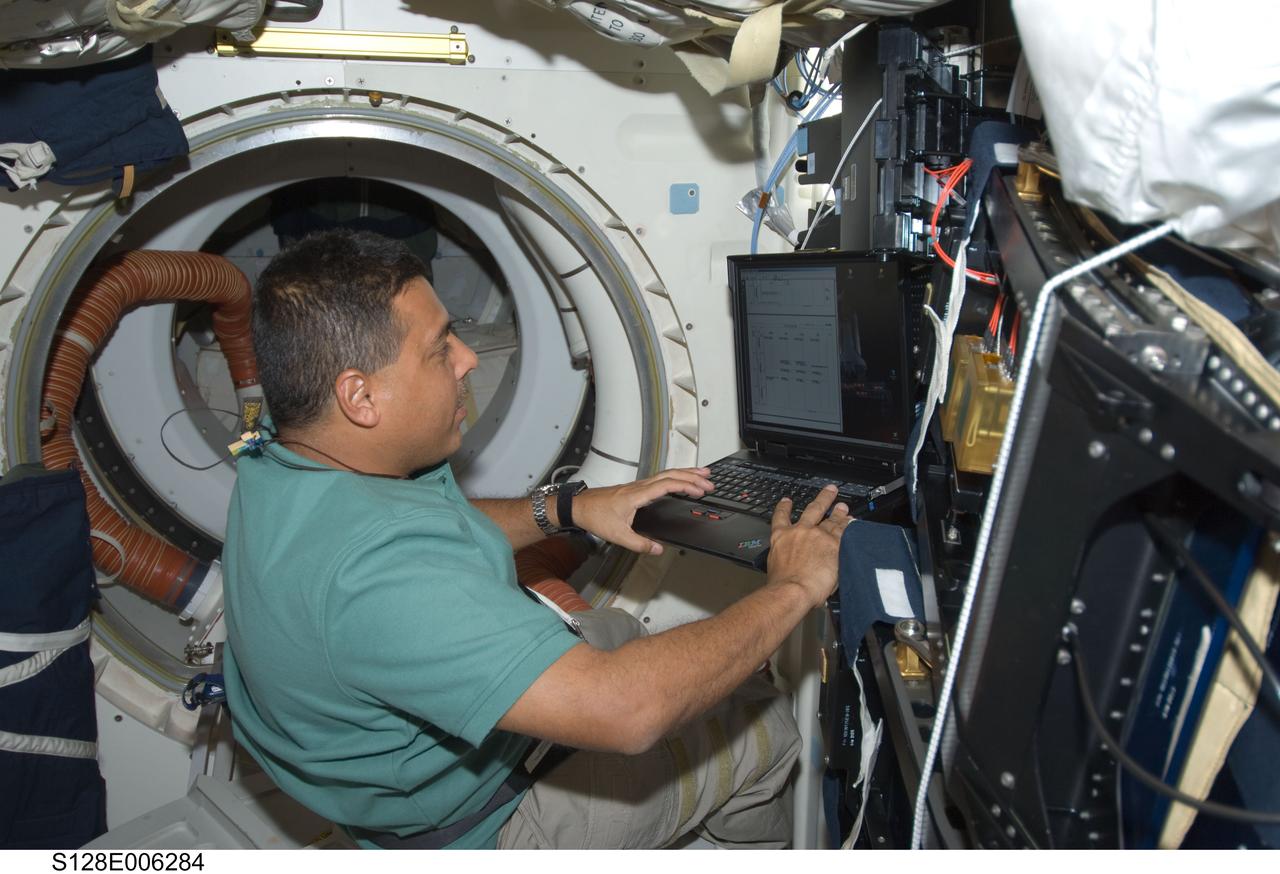 S128-E-006284 (29 Aug. 2009) --- Astronaut Jose Hernandez, STS-128 mission specialist, uses a computer on the middeck of Space Shuttle Discovery during flight day two activities.