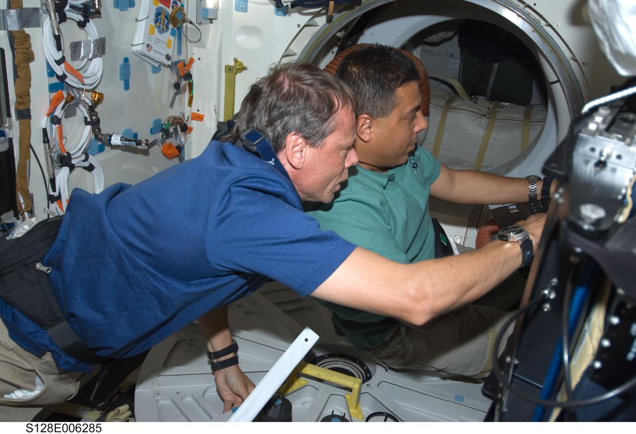 S128-E-006285 (29 Aug. 2009) --- European Space Agency astronaut Christer Fuglesang (left) and NASA astronaut Jose Hernandez, both STS-128 mission specialists, work on the middeck of Space Shuttle Discovery during flight day two activities.