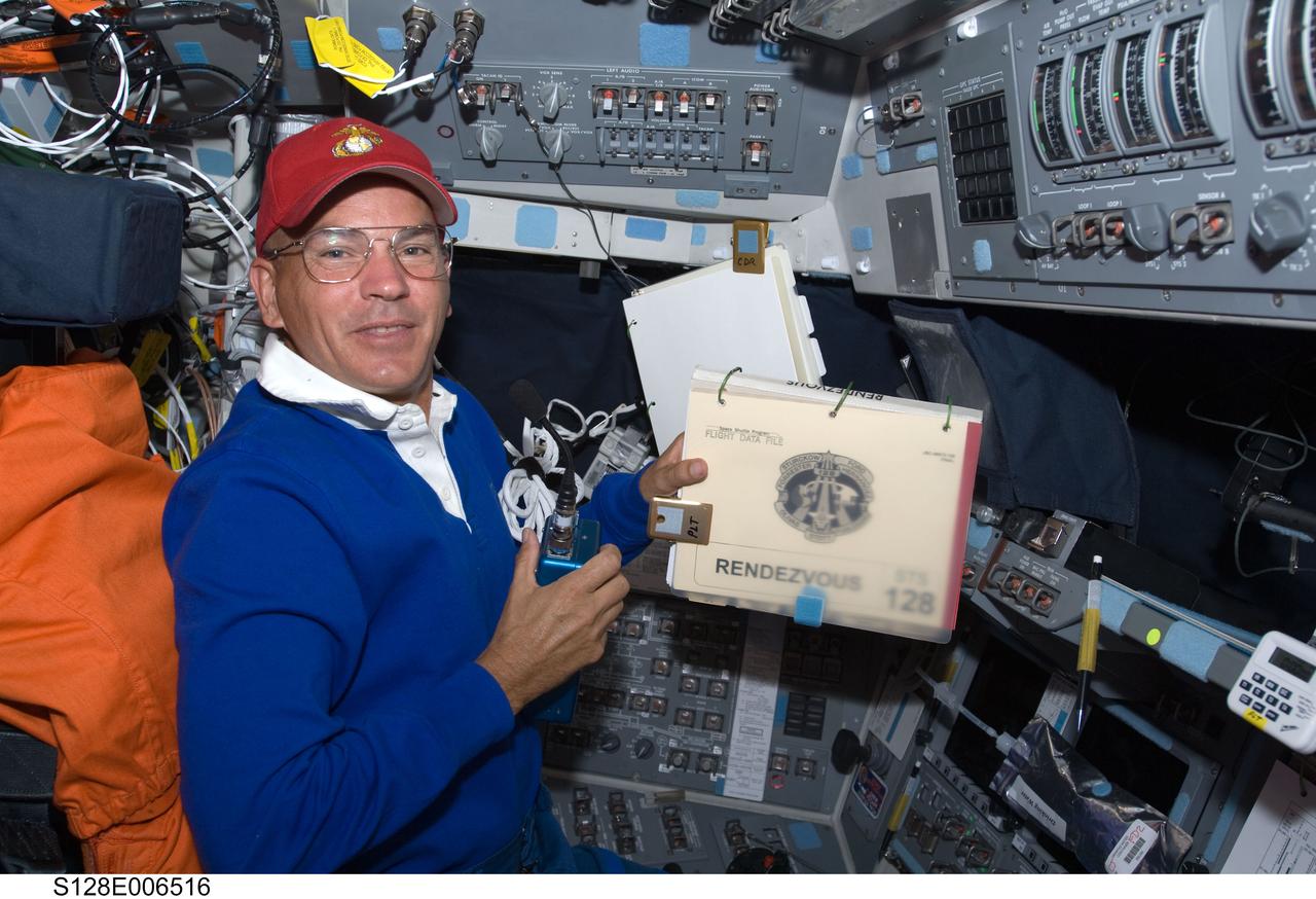 S128-E-006516 (29 Aug. 2009) --- Astronaut Rick Sturckow, STS-128 commander, holds a rendezvous procedure manual while occupying the commander’s station on the forward flight deck of Space Shuttle Discovery during flight day two activities.
