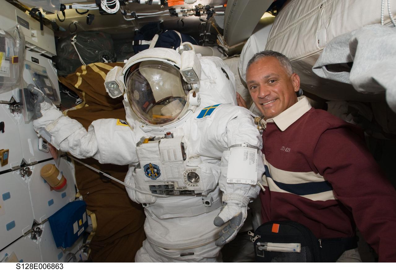 S128-E-006863 (30 Aug. 2009) --- Astronaut John “Danny” Olivas, STS-128 mission specialist, poses for a photo with an Extravehicular Mobility Unit (EMU) spacesuit on the middeck of the Space Shuttle Discovery during flight day three activities.