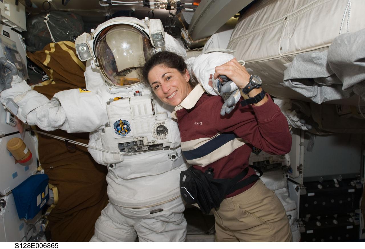 S128-E-006865 (30 Aug. 2009) --- Astronaut Nicole Stott, STS-128 mission specialist, poses for a photo with an Extravehicular Mobility Unit (EMU) spacesuit on the middeck of the Space Shuttle Discovery during flight day three activities.