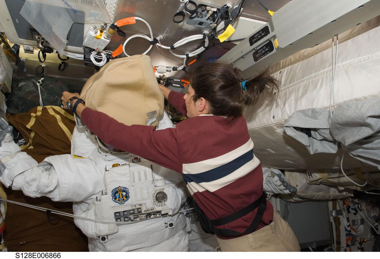 S128-E-006866 (30 Aug. 2009) --- Astronaut Nicole Stott, STS-128 mission specialist, works with an Extravehicular Mobility Unit (EMU) spacesuit on the middeck of the Space Shuttle Discovery during flight day three activities.